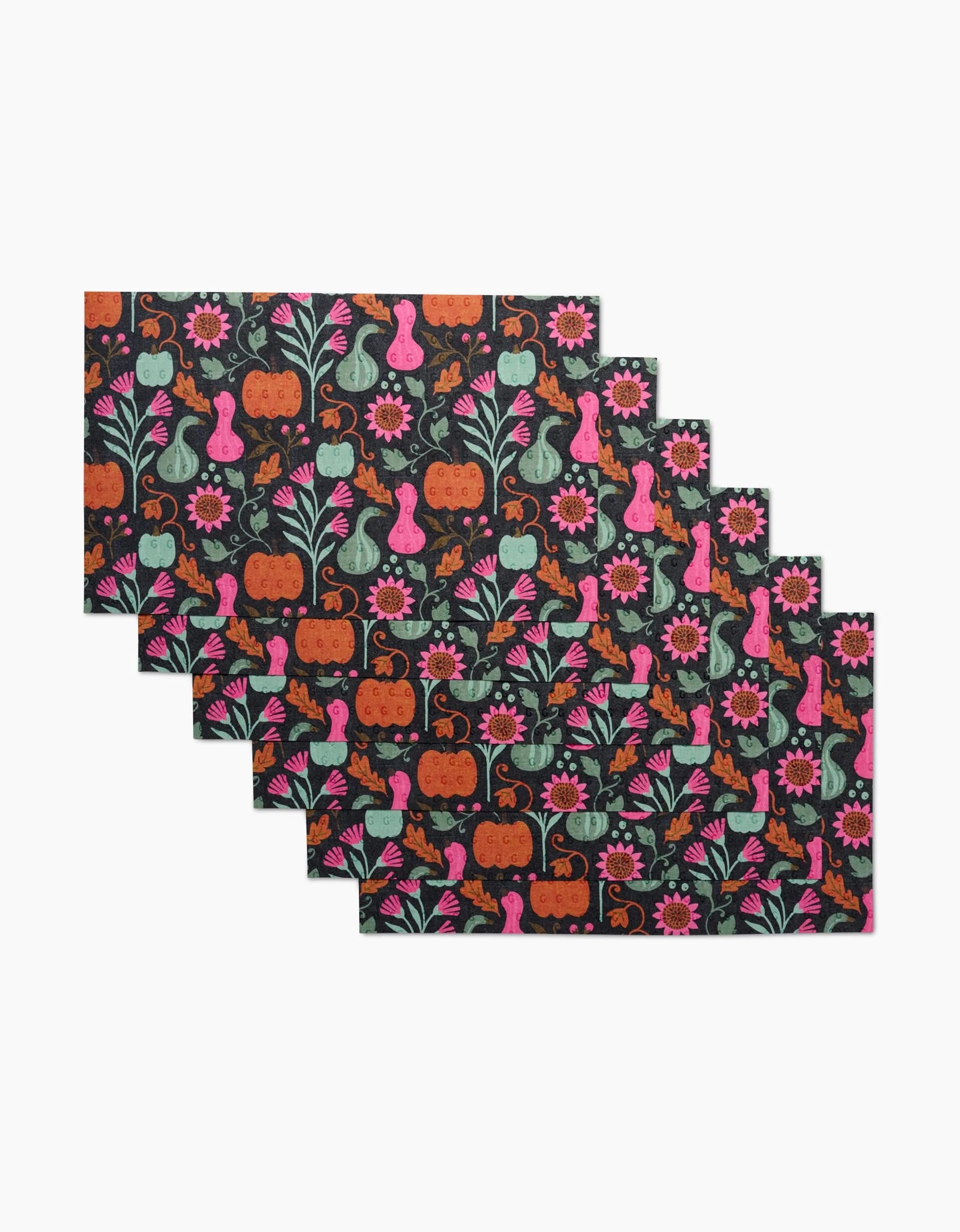 Set of five rectangular Amy MacCready Oakley placemats featuring pumpkins, gourds, flowers, and leaves in orange, pink, teal, and green on a dark background—great to pair with eco-friendly kitchen towels.