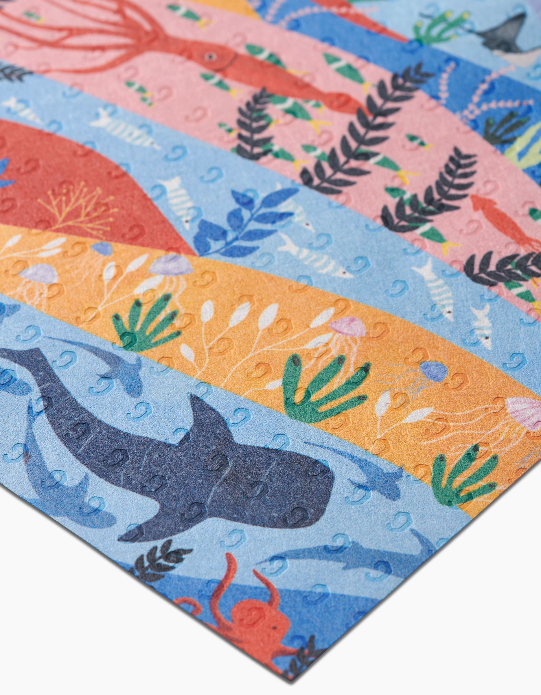 A close-up of Ceyda Alasar’s Oceans puzzle, featuring illustrated sea creatures against blue and orange underwater scenes, made from eco-friendly post-consumer recycled materials.