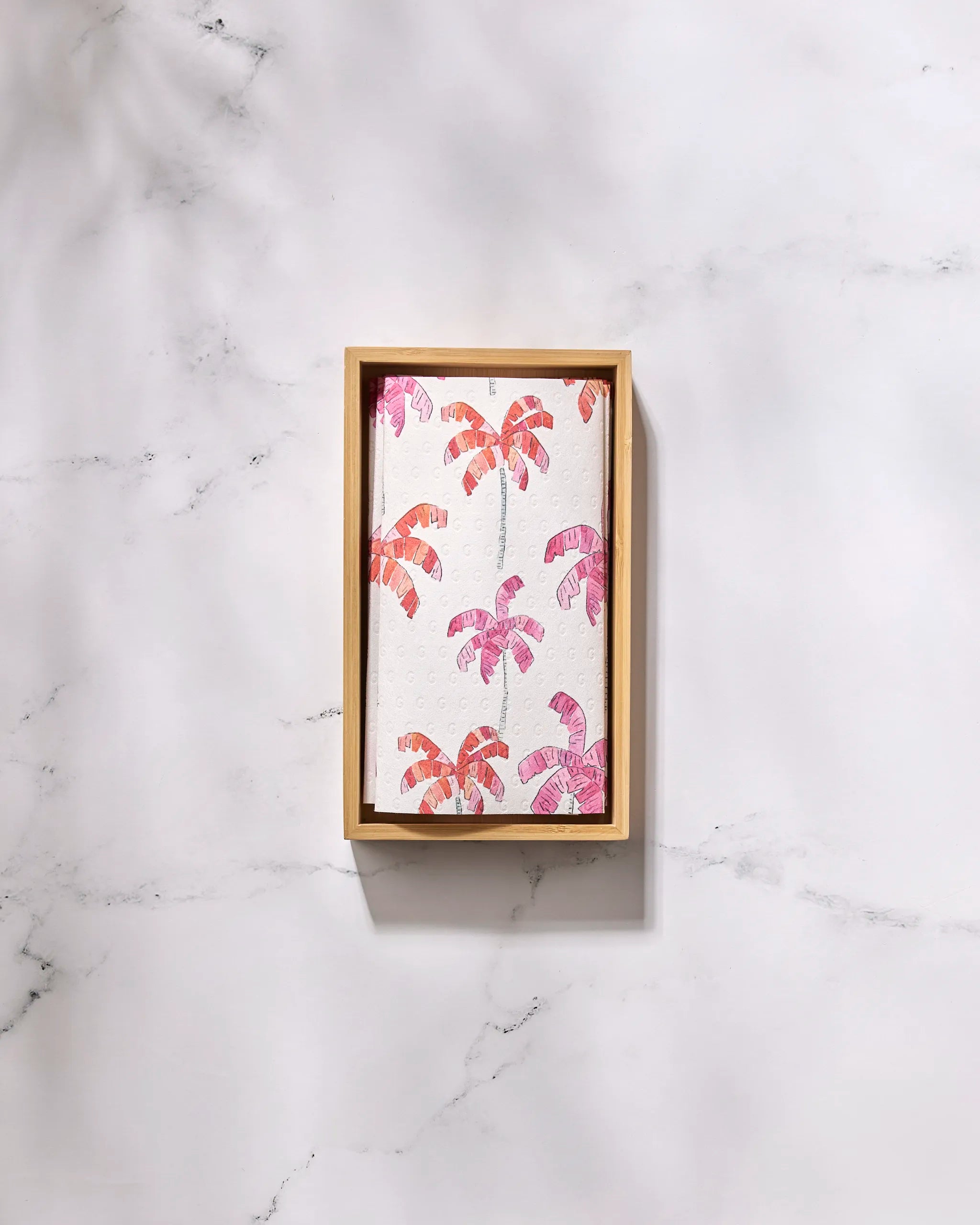 The Pink Palms tray by GEOMETRY features a white base with pink and orange palm tree designs—ideal for stylishly serving eco-friendly kitchen towels or reusable paper towels on any light marble surface.