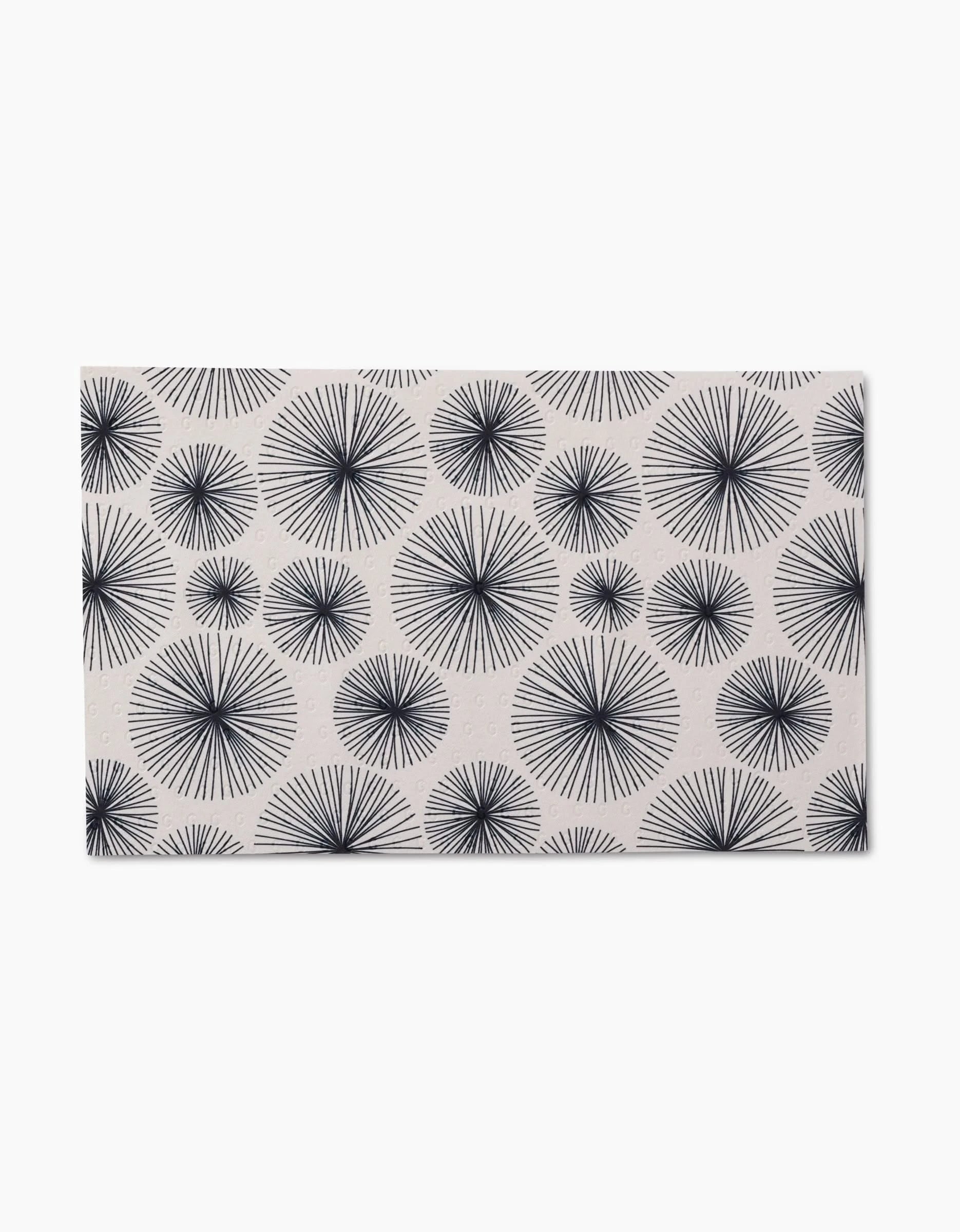 The GEOMETRY Pop Of Color mat is rectangular with a white background and a repeating pattern of black starbursts in various sizes, crafted from post-consumer recycled materials for an eco-friendly touch.