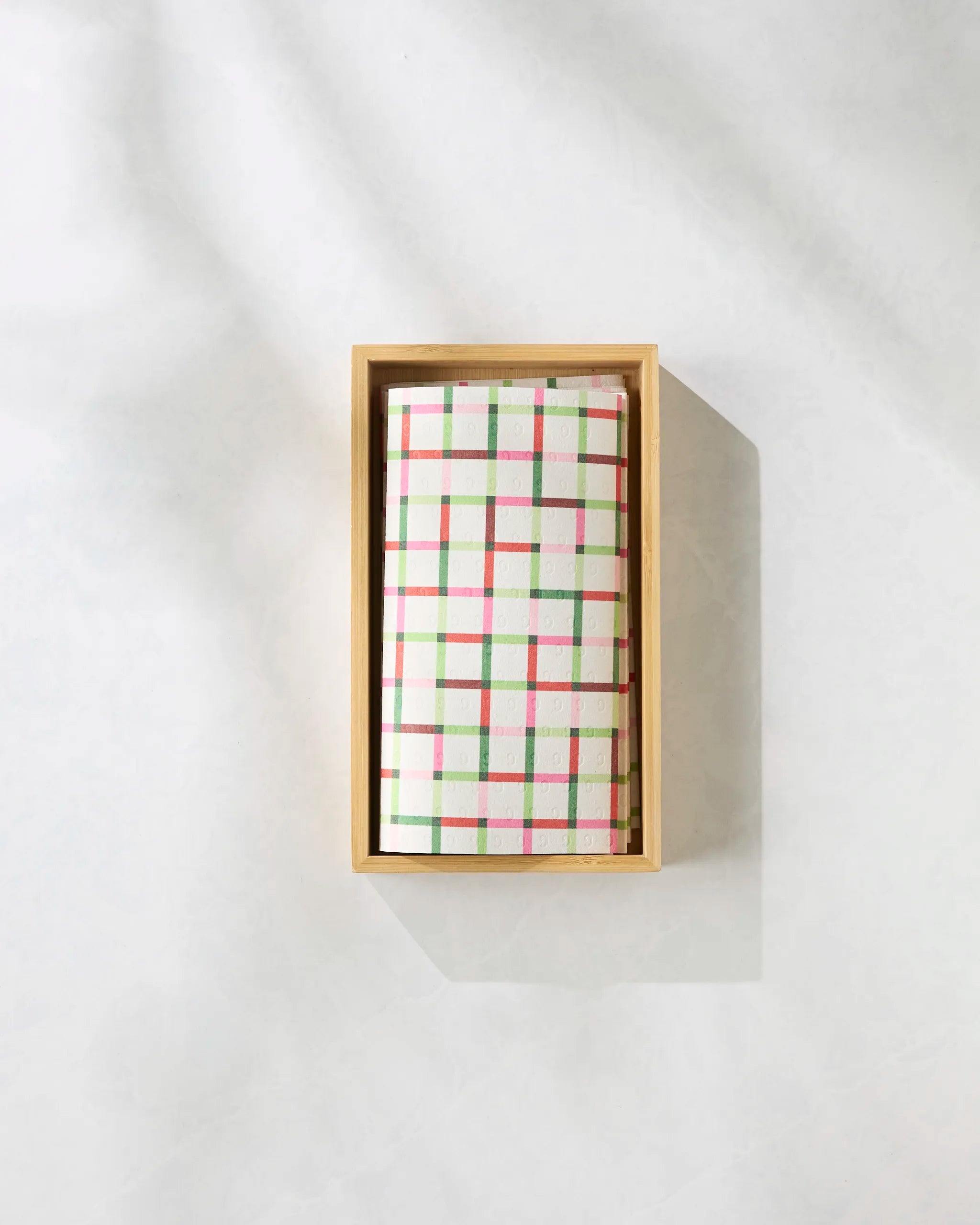 The Season of Joy bar soap by Geometry features a white base with a pink, green, and yellow plaid pattern, elegantly presented in a light wooden box—an ideal complement to eco-friendly paper towels for the sustainable home.