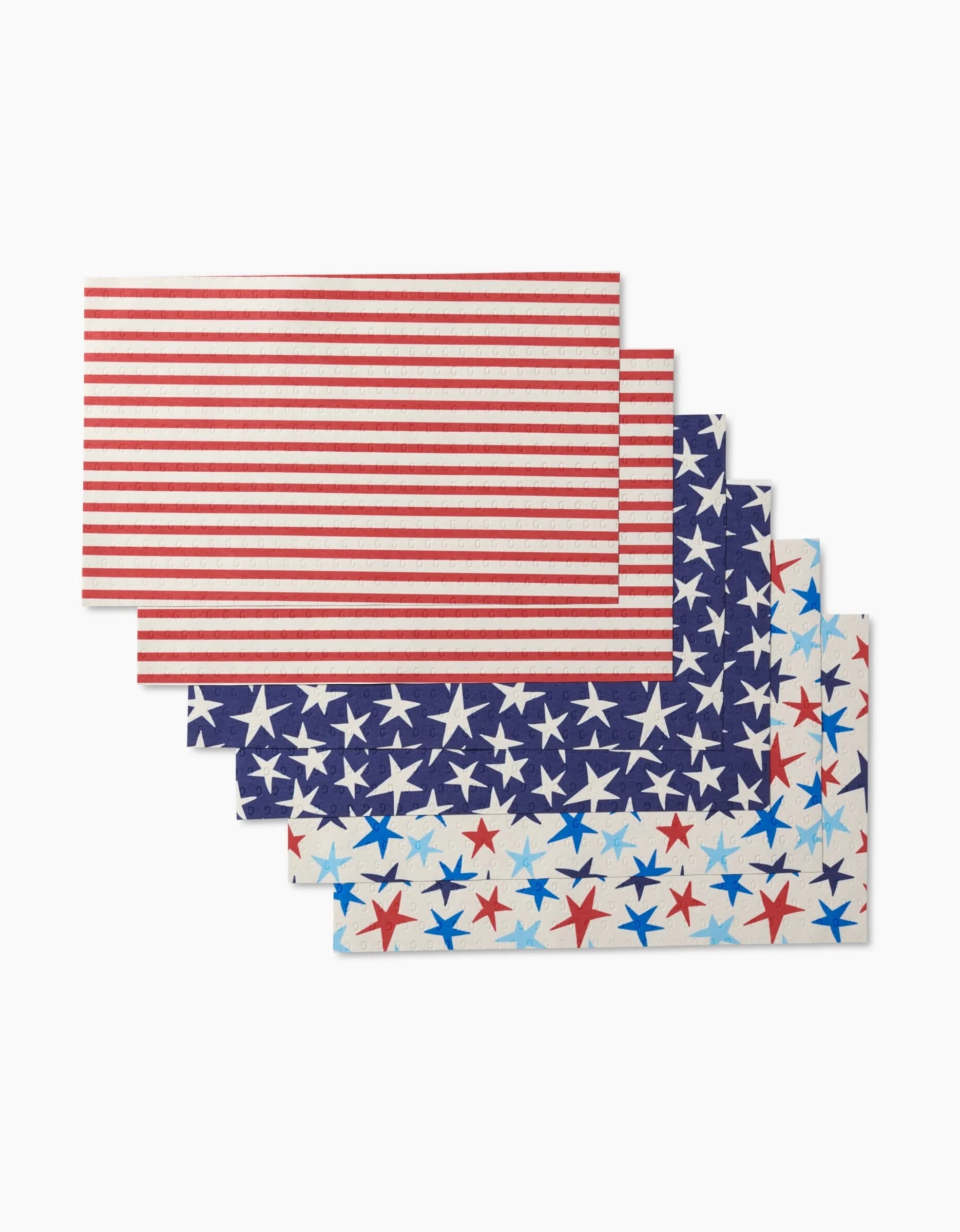 Four “Seeing Stars” rectangular placemats by Mindfulnice—two with red and white stripes, two blue with stars—made from eco-friendly post-consumer recycled materials, are stacked in a staggered display on a white background.