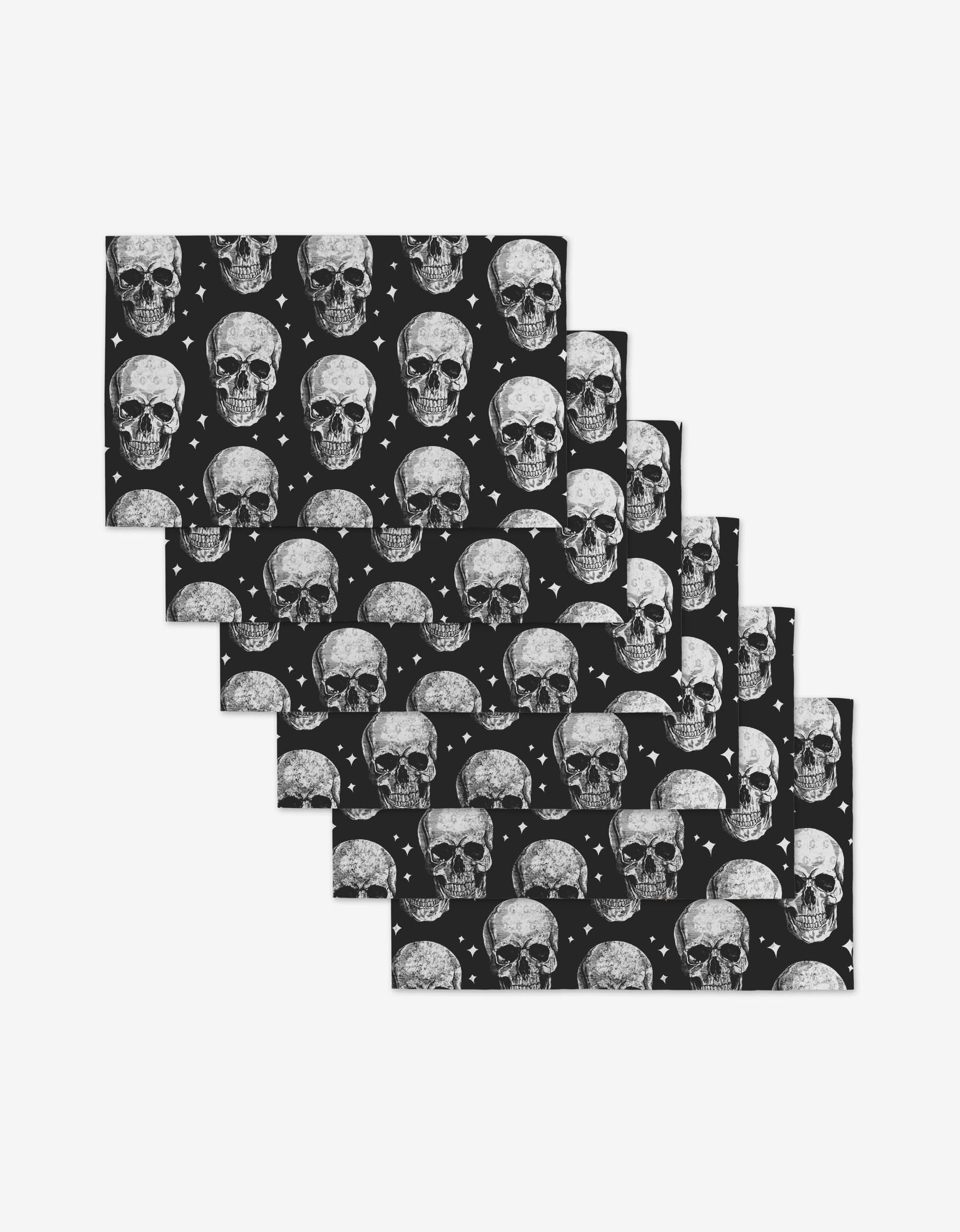The GEOMETRY Skulls set includes six rectangular mats with a repeating white skull and diamond pattern on black, made from eco-friendly post-consumer recycled materials. Mats are stacked in a staggered, overlapping arrangement.