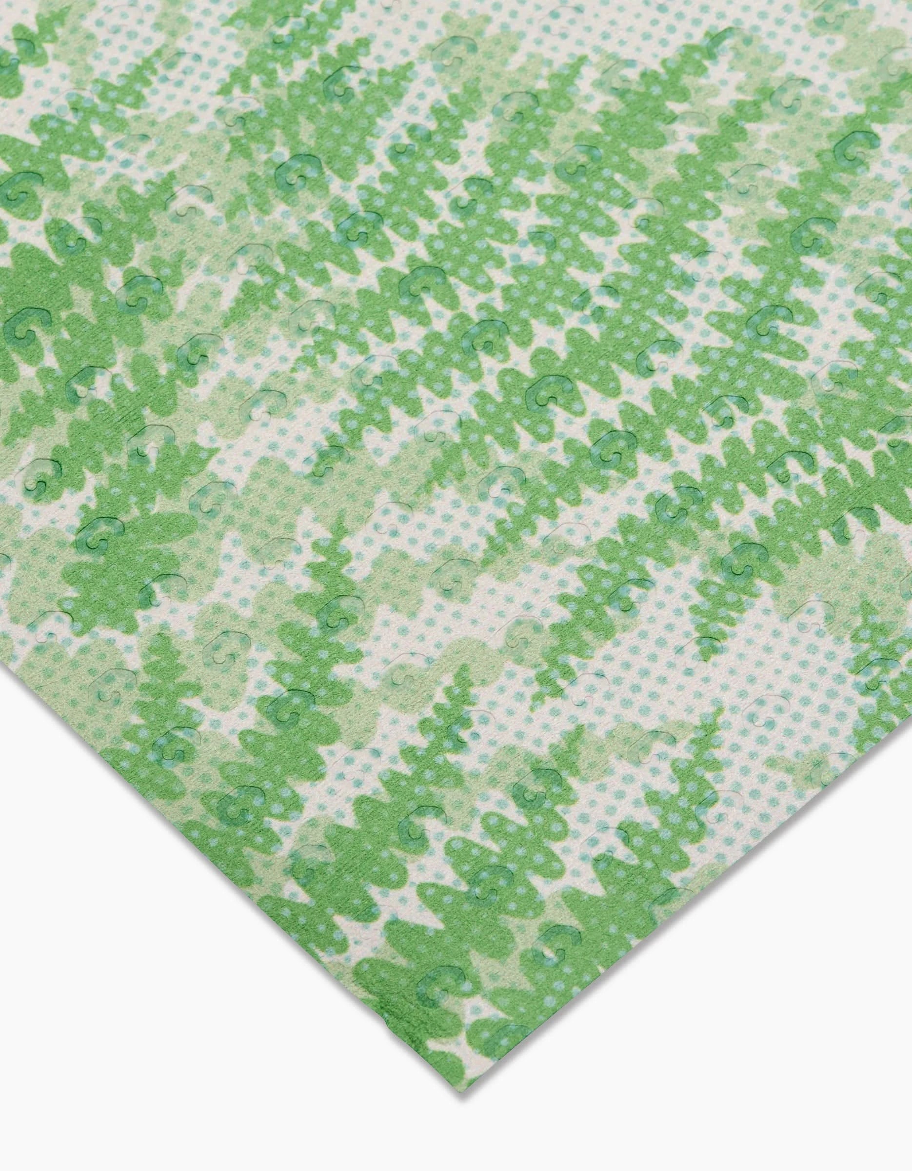 The GEOMETRY Swaying Leaf reusable paper towel features green fern-like patterns on a white background with light blue dots, made from eco-friendly materials and shown angled toward the bottom of the image.