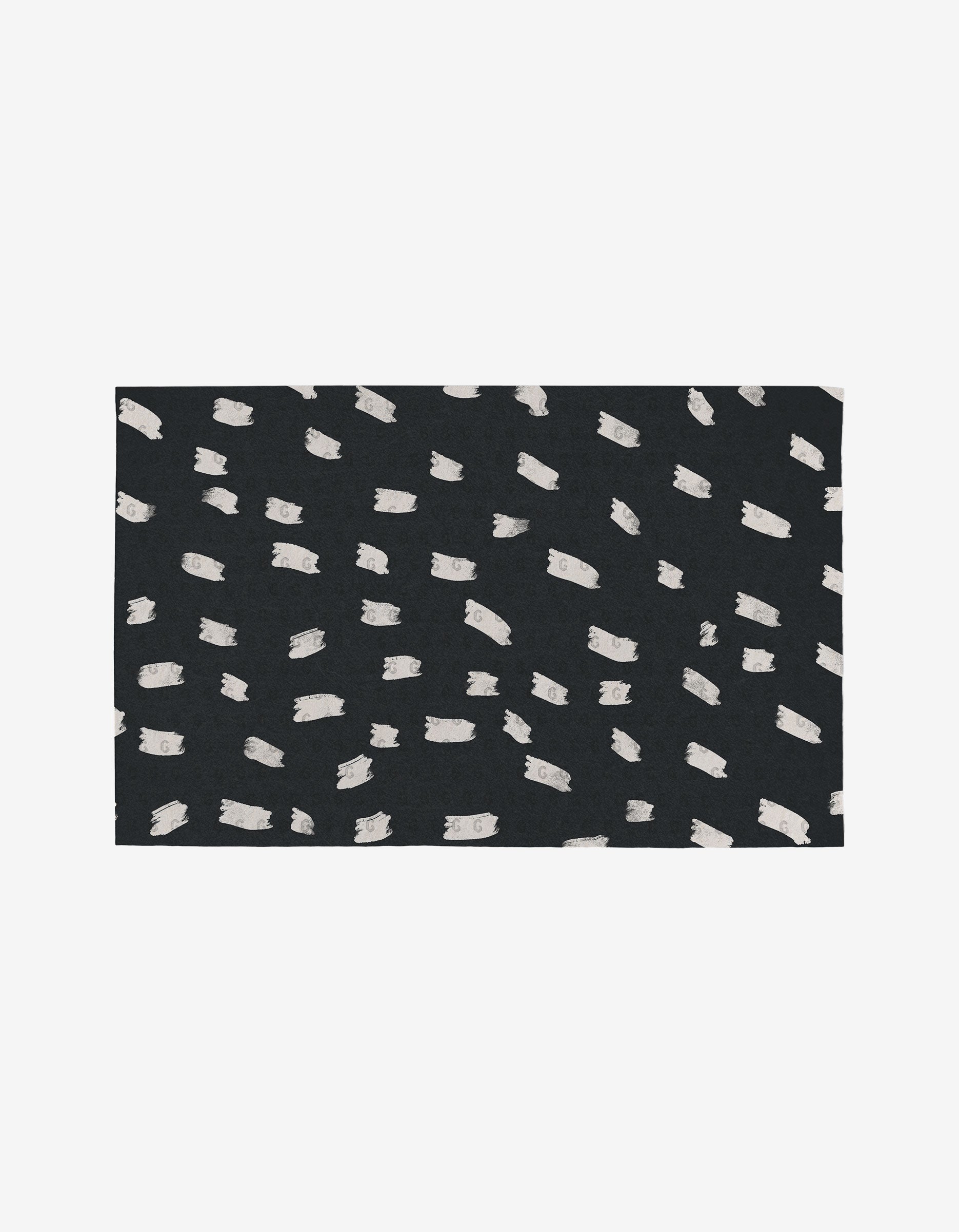 The Tess And Dark rug by GEOMETRY is a rectangular, black eco-friendly rug with an abstract pattern of irregular white brushstrokes, crafted from post-consumer recycled materials.