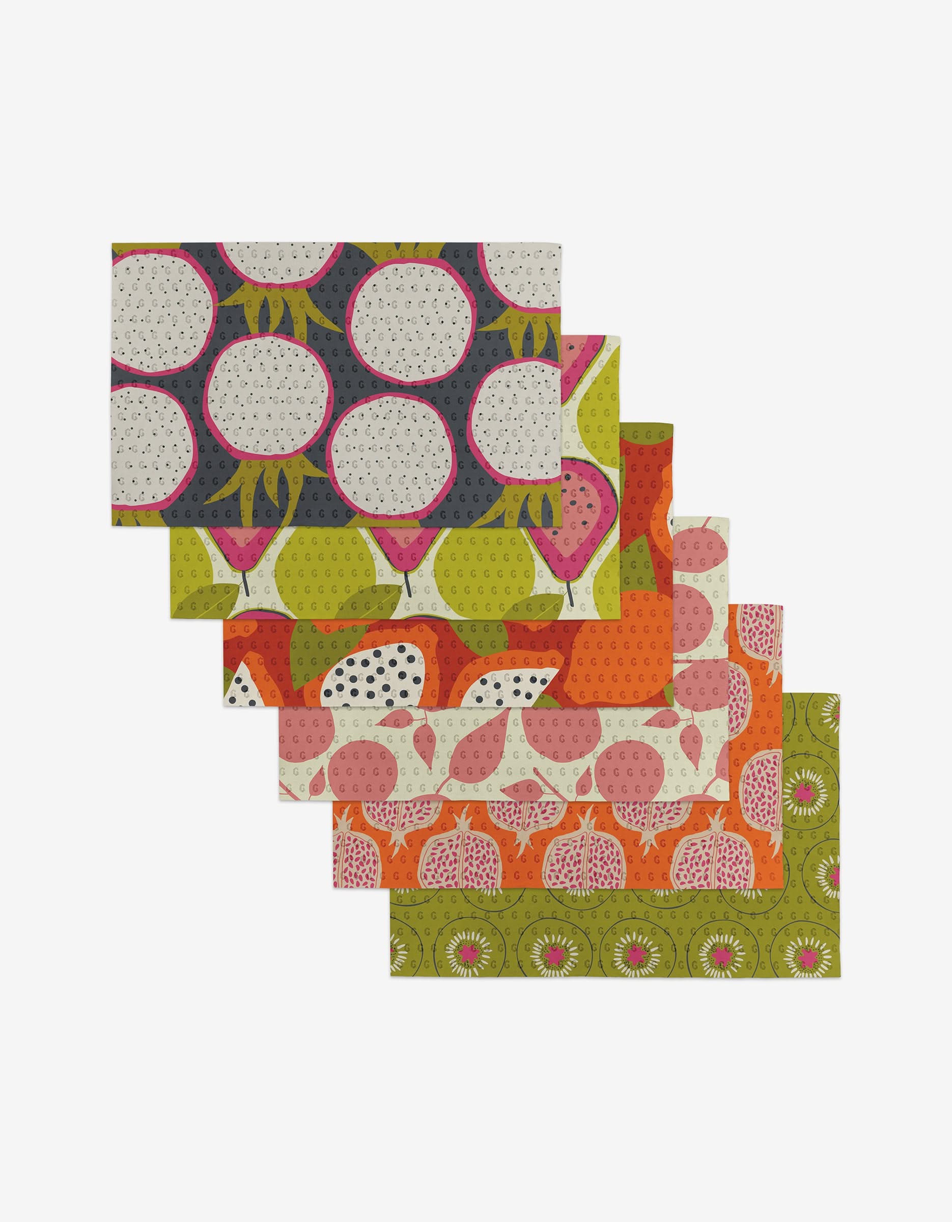 Six Lizzie Clark Tropical Fruit placemats with vibrant green, orange, pink, and navy fruit patterns are fanned out on a white background—each made from eco-friendly materials.