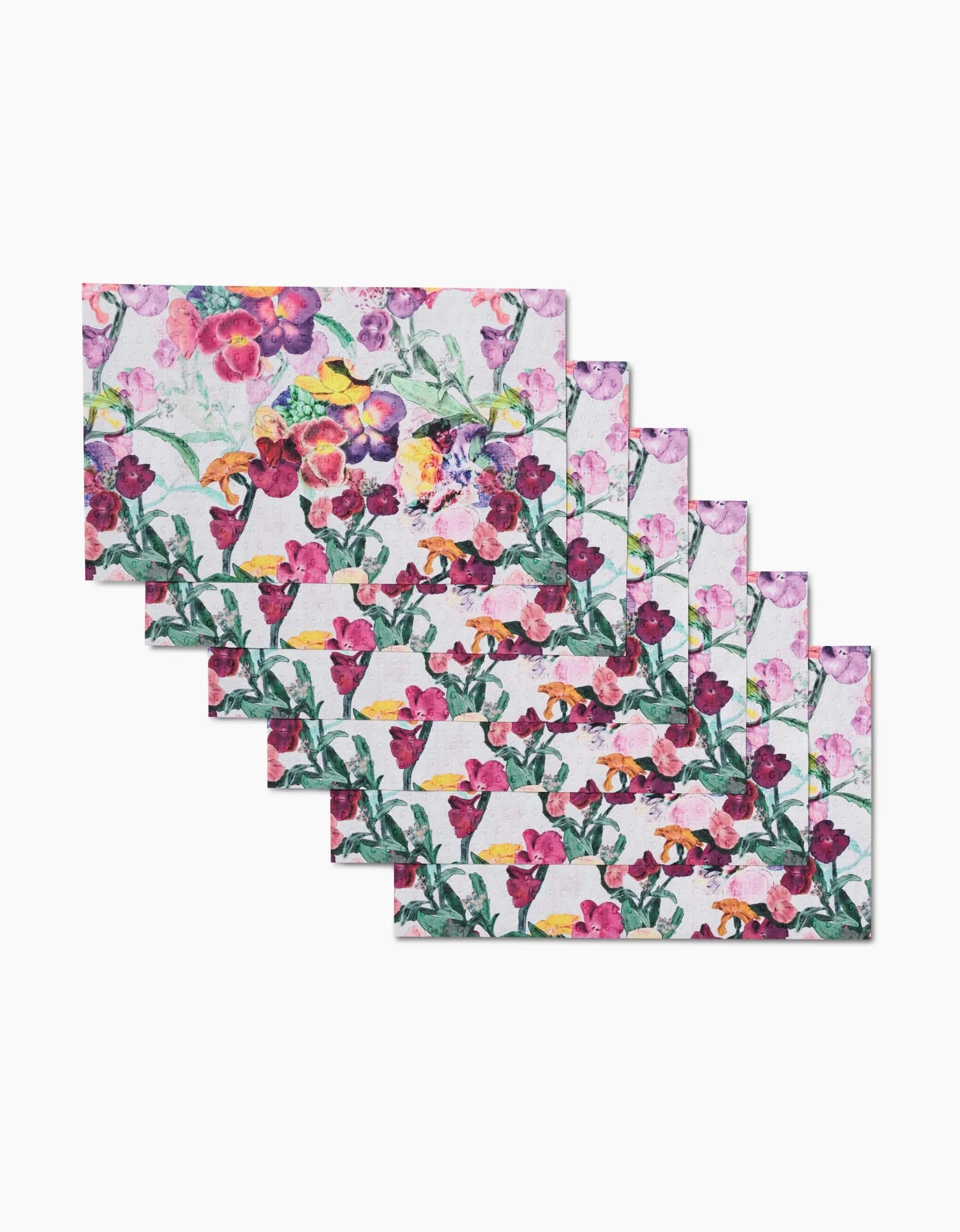 A set of six Wallflower rectangular placemats by Pascale Dilger, each with a vibrant pink, purple, and yellow floral pattern—perfect for pairing with reusable kitchen towels in any eco-friendly home.