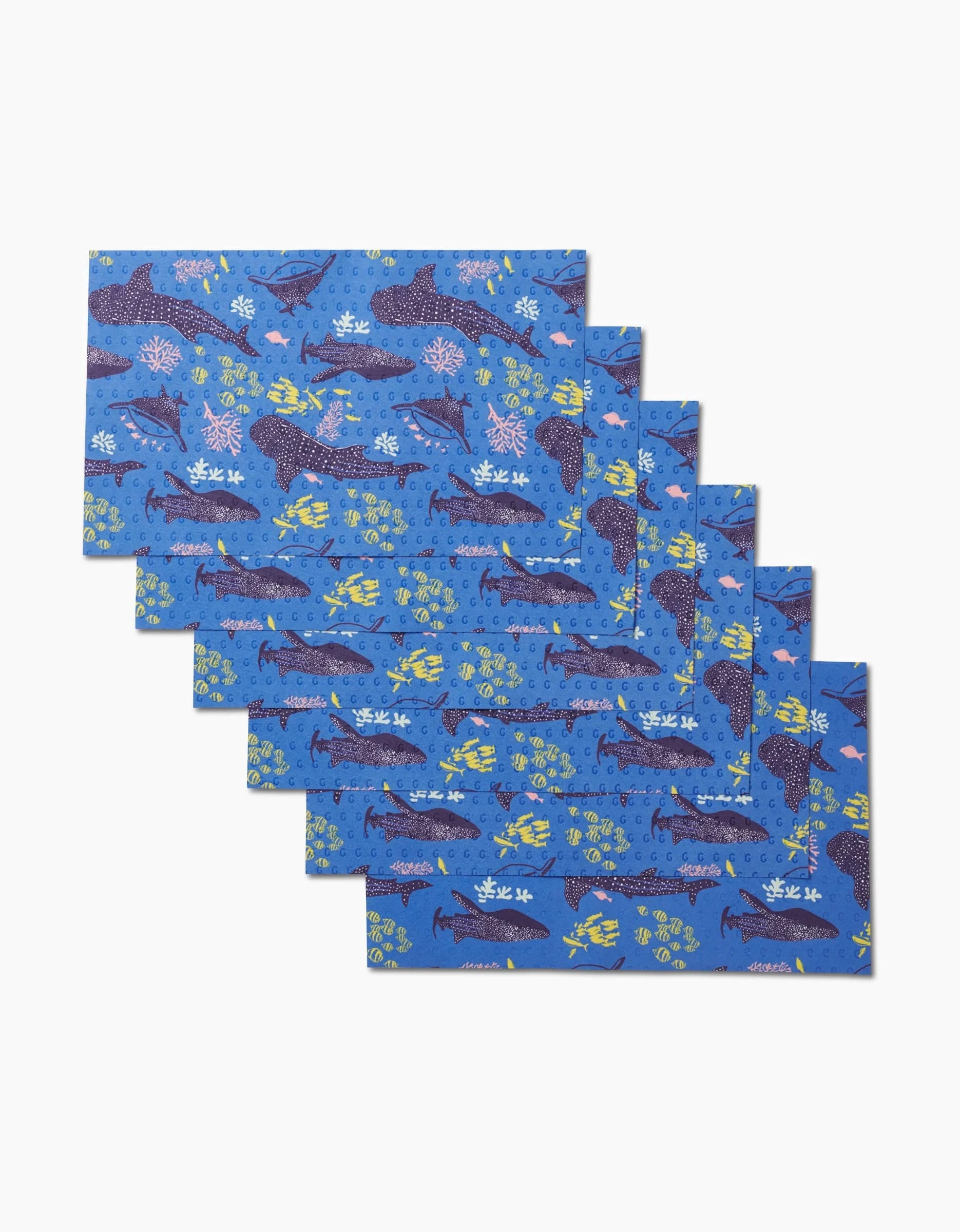 Six rectangular blue Whale Shark placemats by Elisabeth Wing feature vibrant sea creature designs—sharks, turtles, and coral—in a fanned-out stack. An eco-friendly, reusable alternative to Not Paper Towels.