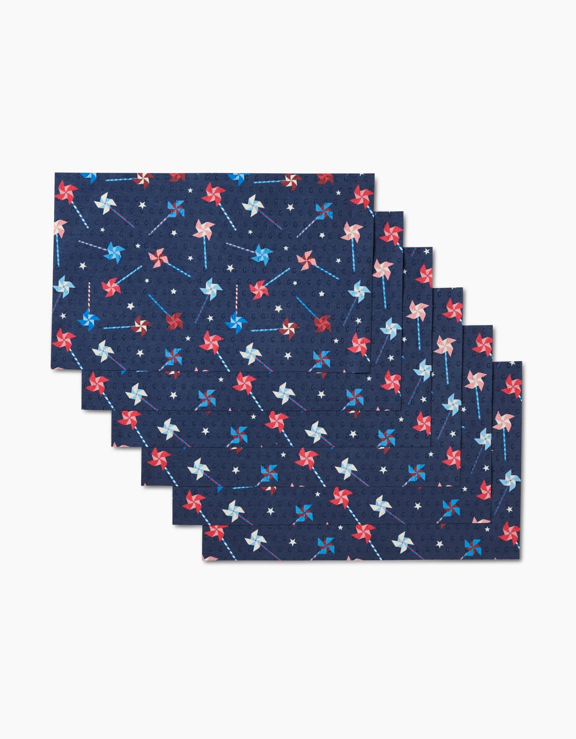 Six reusable Whirlwind Pins placemats by Rebecca Bobko feature a rectangular navy design with red, white, and blue pinwheels and small white stars—an eco-friendly alternative to paper towels. Includes six stacked placemats.
