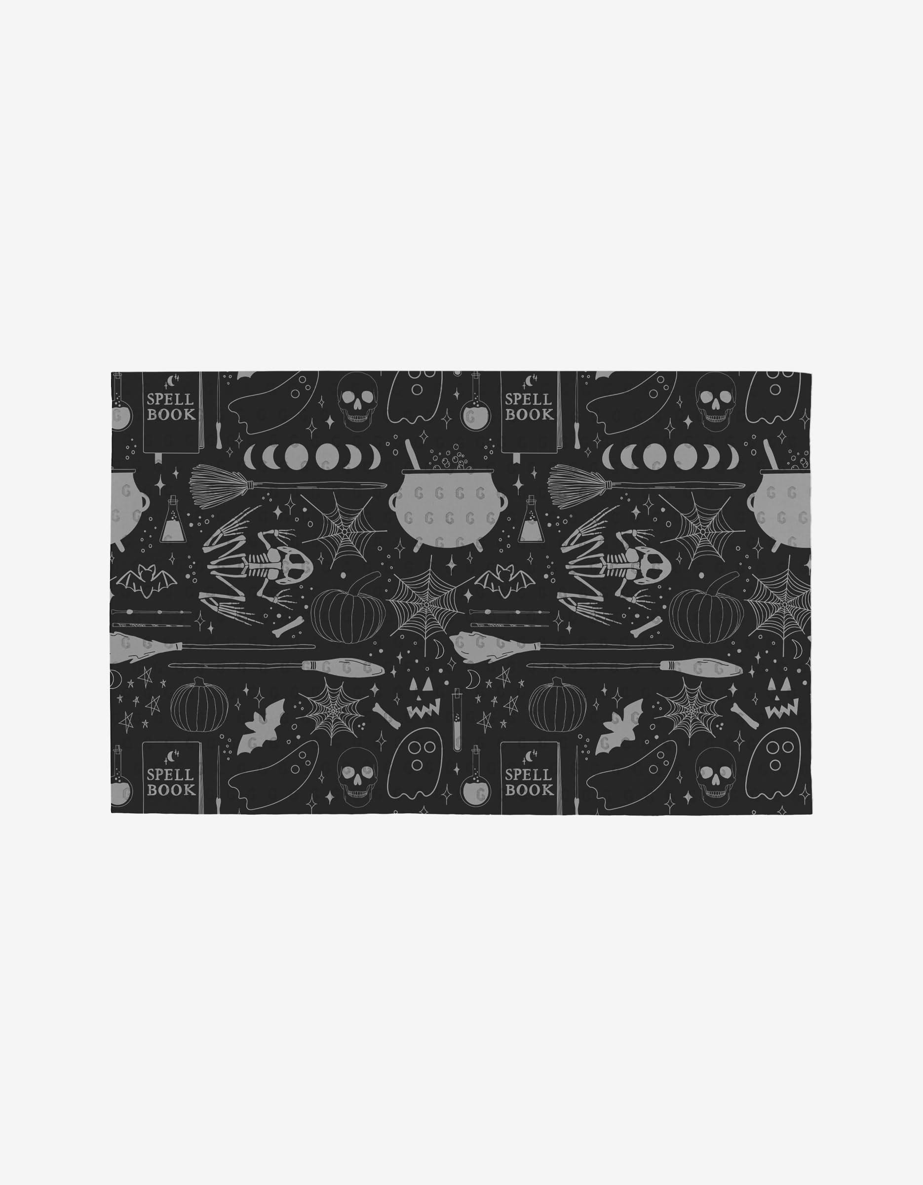 The Witches Brew Not Paper Towel by Rosa Kichline features a Halloween-themed black and gray pattern with skulls, bats, pumpkins, moons, and books—made from eco-friendly post-consumer recycled materials.