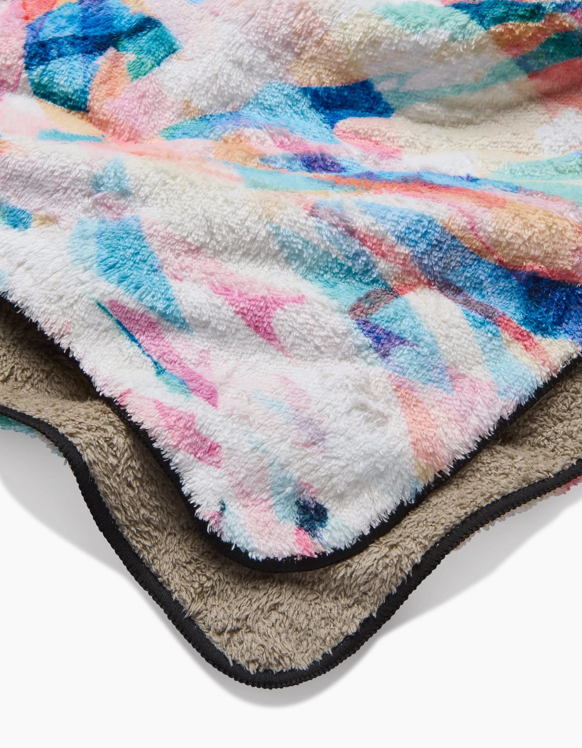 A close-up of two soft, fluffy Rachel Parker blankets: the top, Abstract Jungle, features a colorful pastel pattern; the bottom is beige with a black border and made from recycled materials.