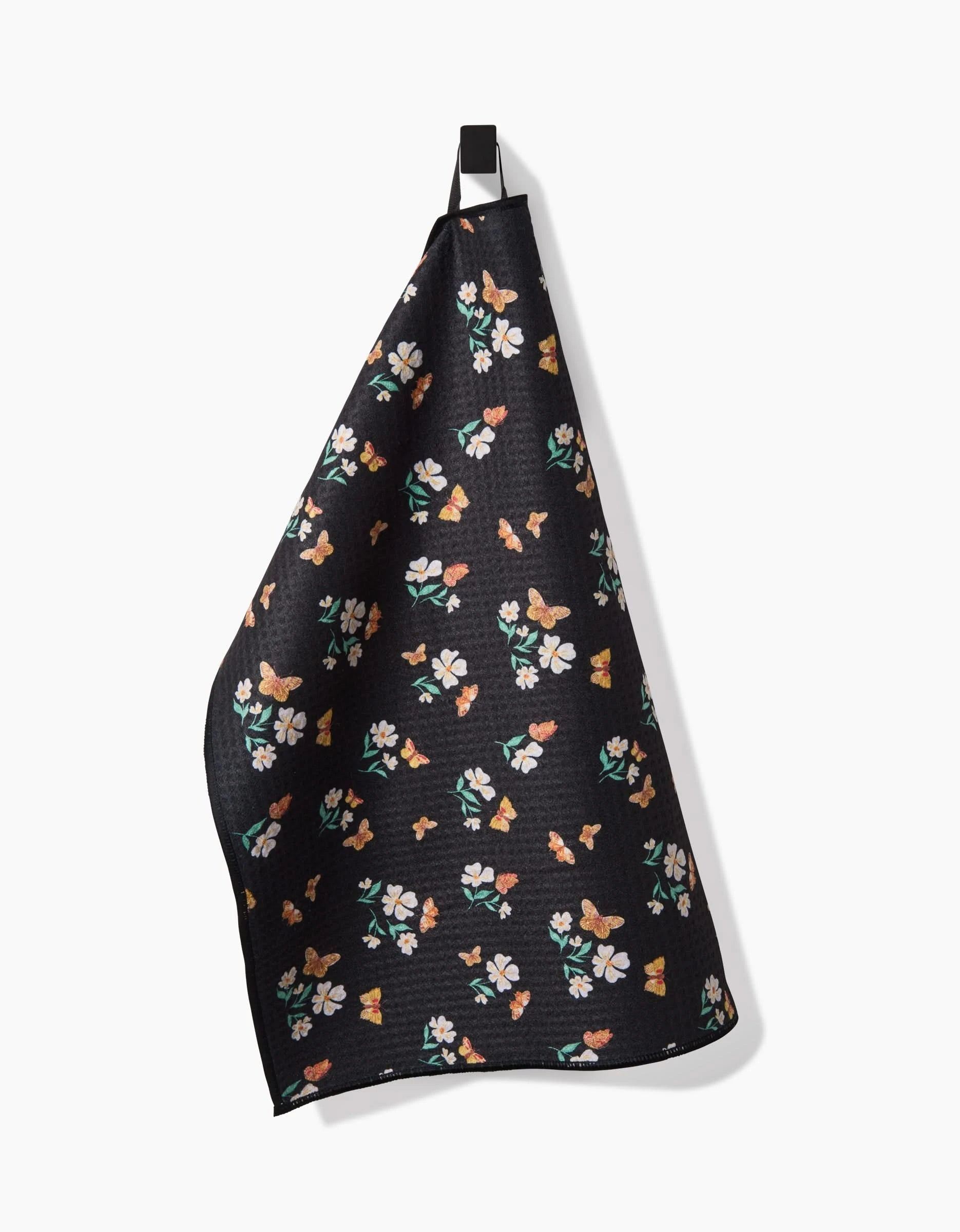 The Butterfly Garden dish towel by Danelys Sidron features ultra-absorbent Geoweave fabric with a vibrant floral and butterfly pattern, shown hanging from a black loop on a plain white background.