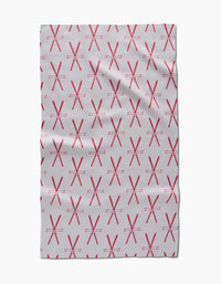 A light gray Becki Owens Vintage Ski Tea Towel with a repeated pattern of red X and star-like shapes in neat rows. Eco-friendly fabric displays visible folds and slight wrinkles.