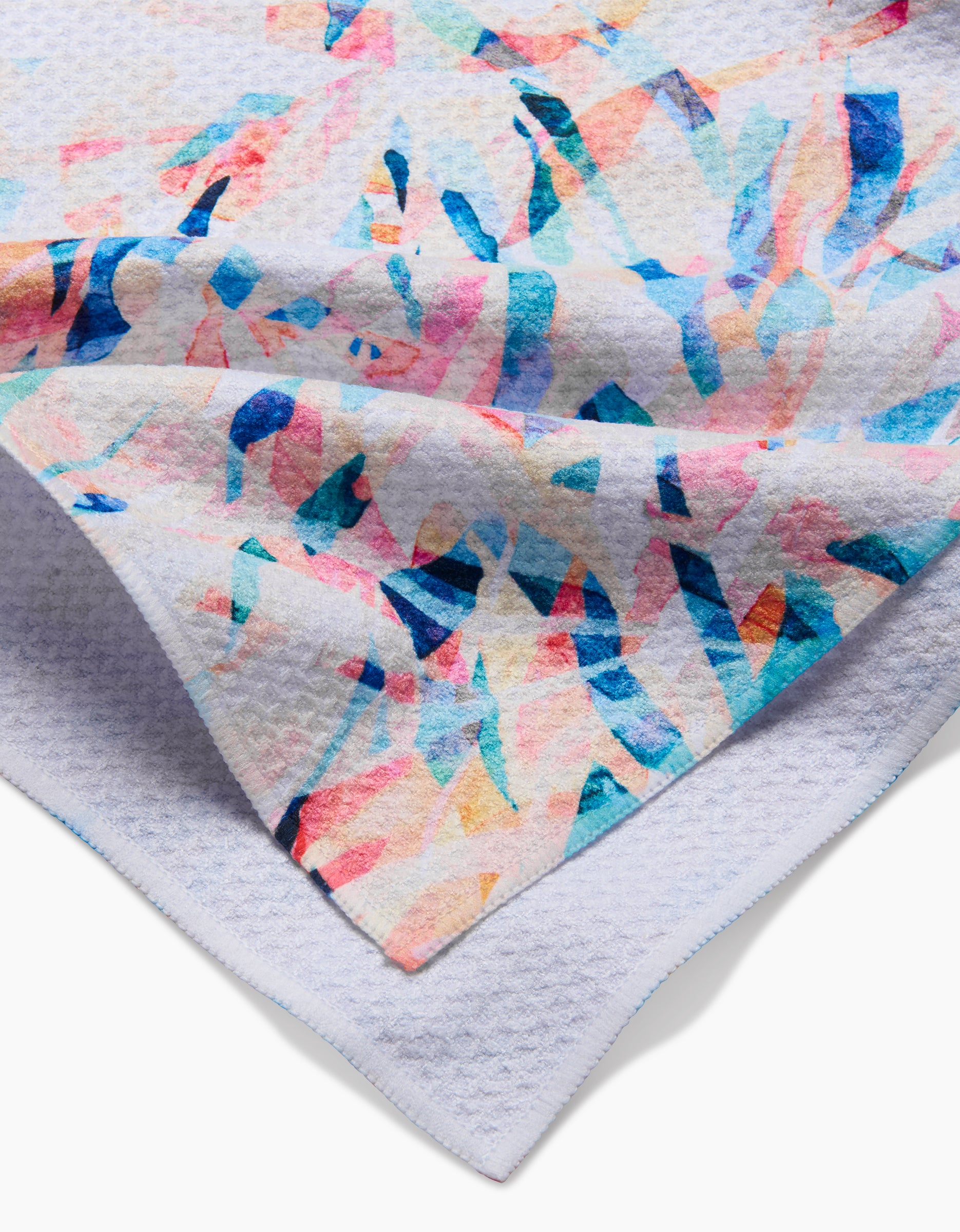A close-up of the Rachel Parker Abstract Jungle tea towel displays its vibrant blue, pink, and orange abstract pattern on white Geoweave fabric, highlighting textured details and neatly folded corners.