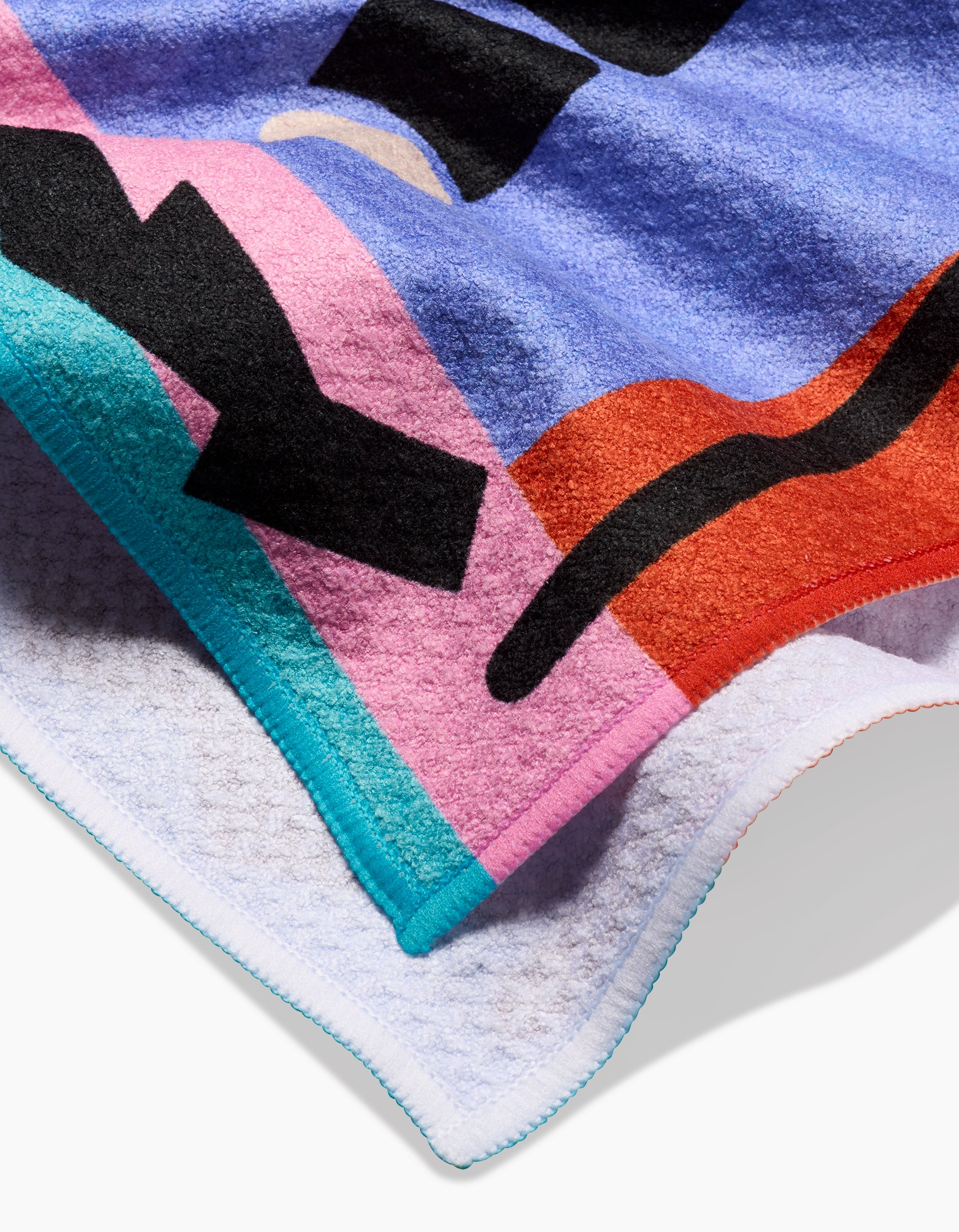 A close-up of the Ariranha tea towel by Camila Leão, featuring colorful abstract shapes and black lines in blue, pink, red, turquoise, and white on textured terry cloth made from recycled materials with stitched edges.