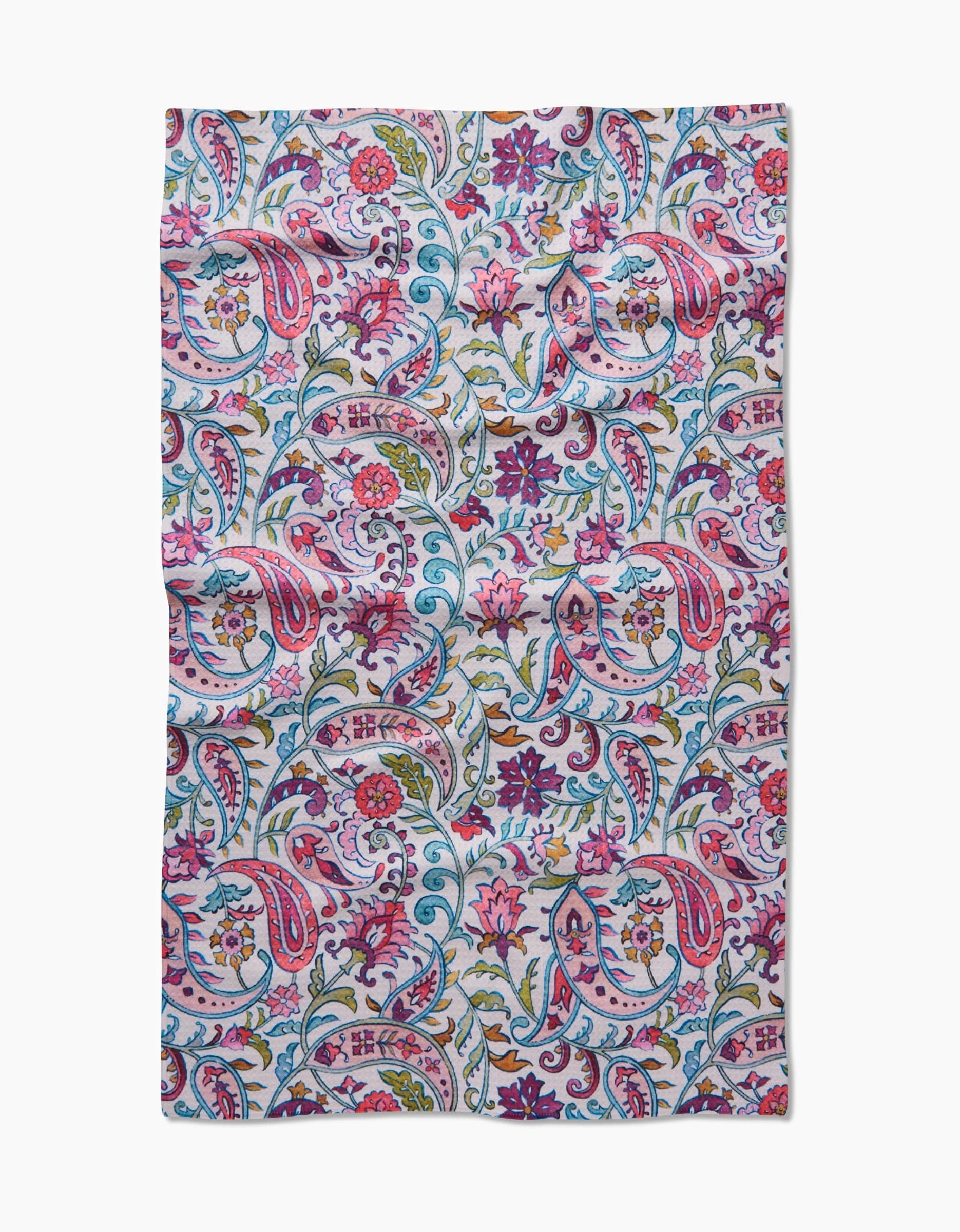 The Bazaar Kitchen Tea Towel by Maayan Alper-Swan features a paisley and floral print in pink, purple, blue, and green on white. Made from recycled materials, the rectangular fabric has a slightly wrinkled look.