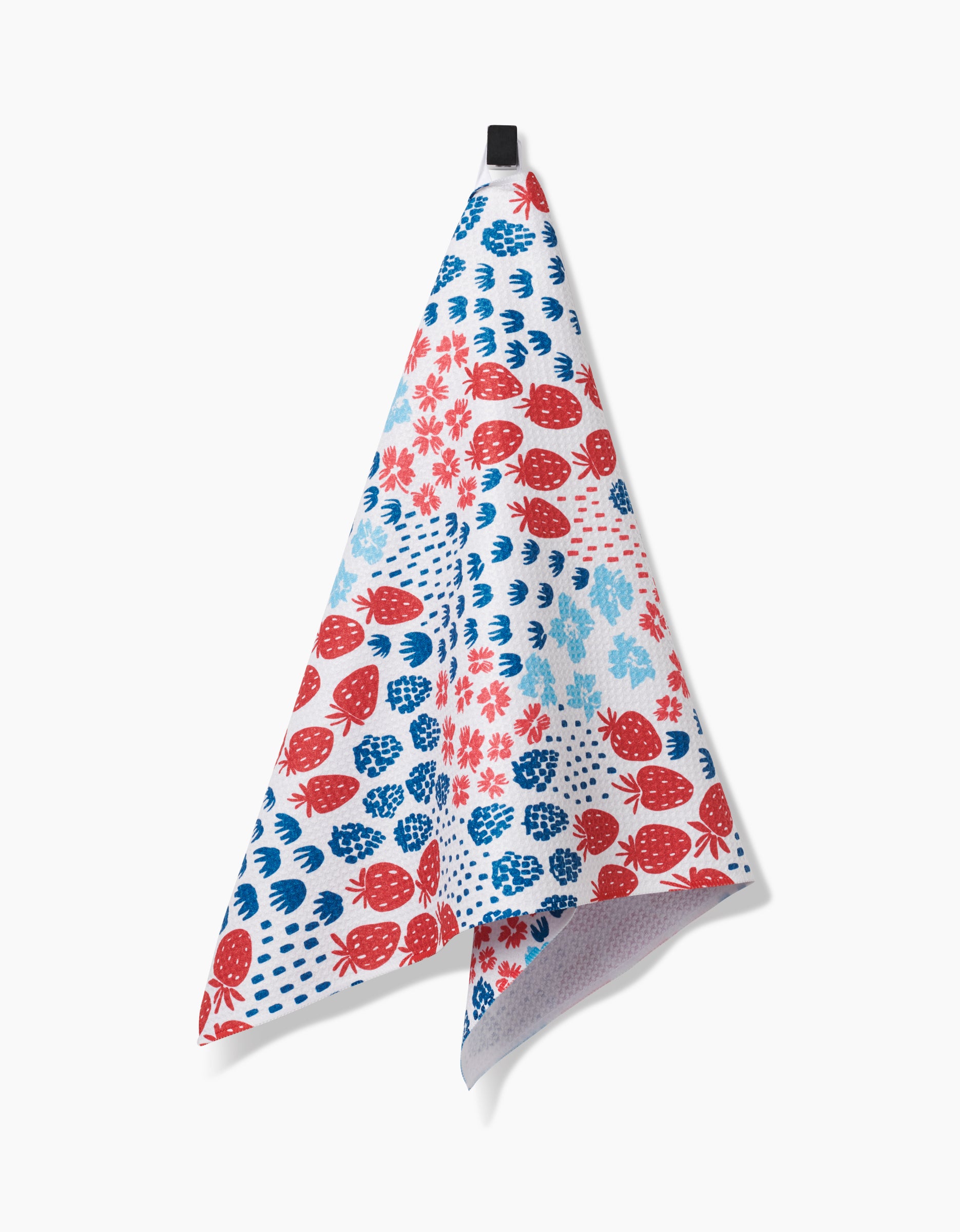 The Berry Meadow tea towel by Hufton Studio, made from recycled materials and adorned with red and blue floral motifs, hangs by a black loop against a plain white background.