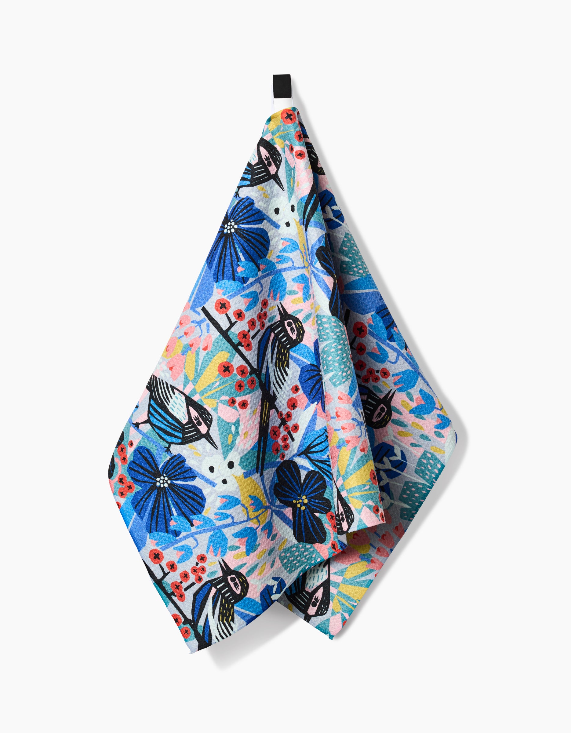 The Birds And Berries tea towel by Masha Volnova features vibrant blue, pink, red, and green floral and leaf patterns, is made from recycled materials, and hangs from a black loop against a white background.