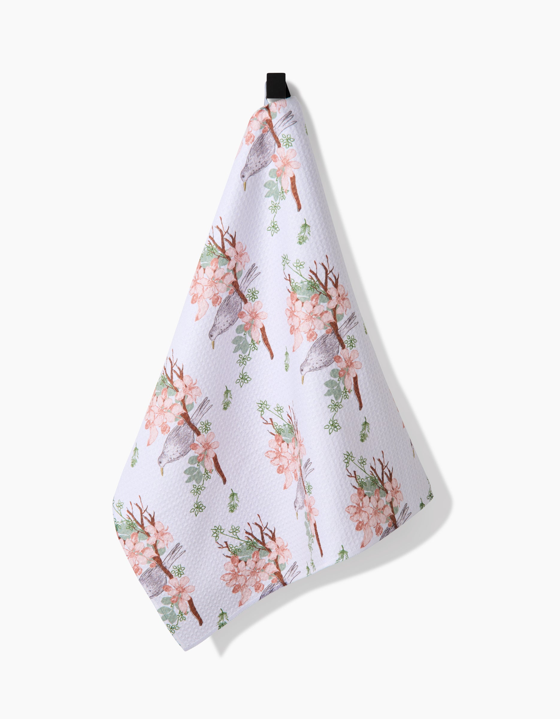 The Linda Fox Blackbird and Blossom dish towel hangs from a black loop, displaying blackbirds and pink blossoms with green leaves on ultra-absorbent Geoweave fabric against a plain white background.