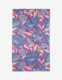 The Blooming Peonies tea towel by Ashley Celena features bold blue and purple flowers, white leaves, and yellow accents on vibrant pink, crafted from ultra-absorbent recycled materials.