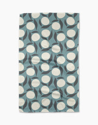 The “Bouncing Blooms” tea towel by Lizzie Clark is a rectangular, blue recycled towel with large white circles and curved black shapes in a modern abstract geometric pattern.