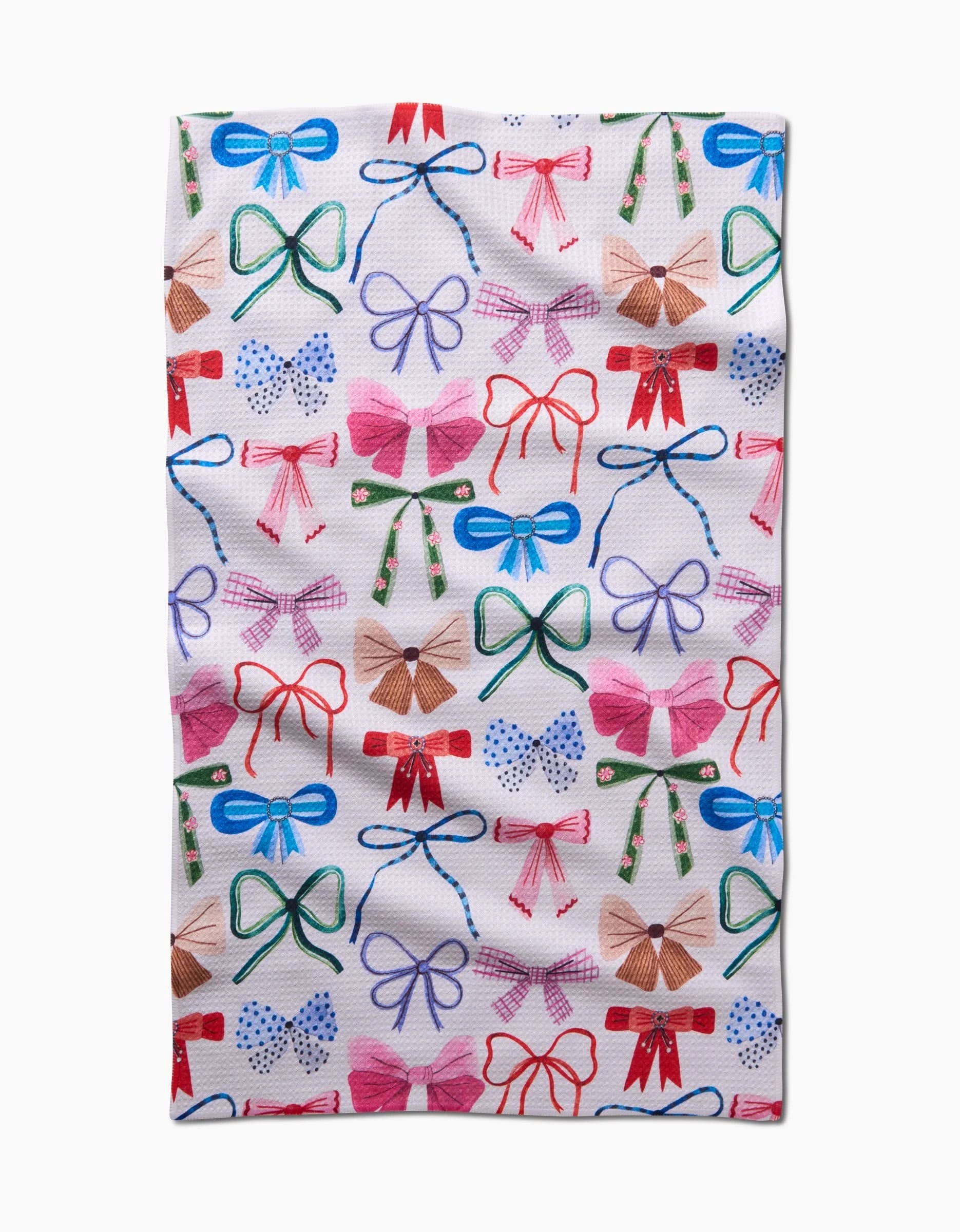The Bows tea towel by Daria Solak features a lively, repeating pattern of colorful bows and ribbons in red, blue, green, pink, and brown on white—crafted from quick-drying recycled materials.