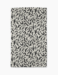 The Brush Strokes Swirls tea towel by Sarah Daugherty features a black and white abstract pattern on an off-white background. Made from recycled materials, it offers a stylish and sustainable choice for your kitchen.