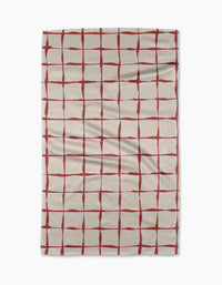 The Brushstroke Checks kitchen towel by Linda Fox is a beige, recycled fabric towel with irregular red grid lines and visible surface creases.