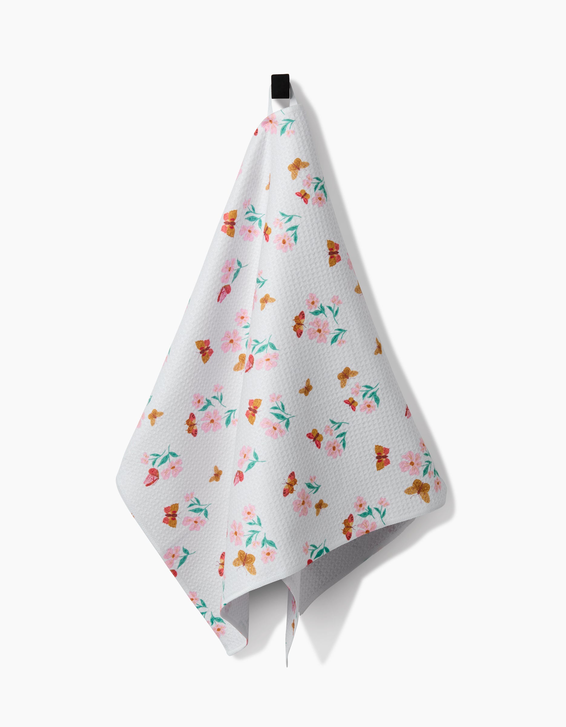 The Danelys Sidron Butterfly Garden Tea Towel, made from Geoweave™ fabric, displays vibrant floral and butterfly patterns and hangs from a black hook against a plain white background.