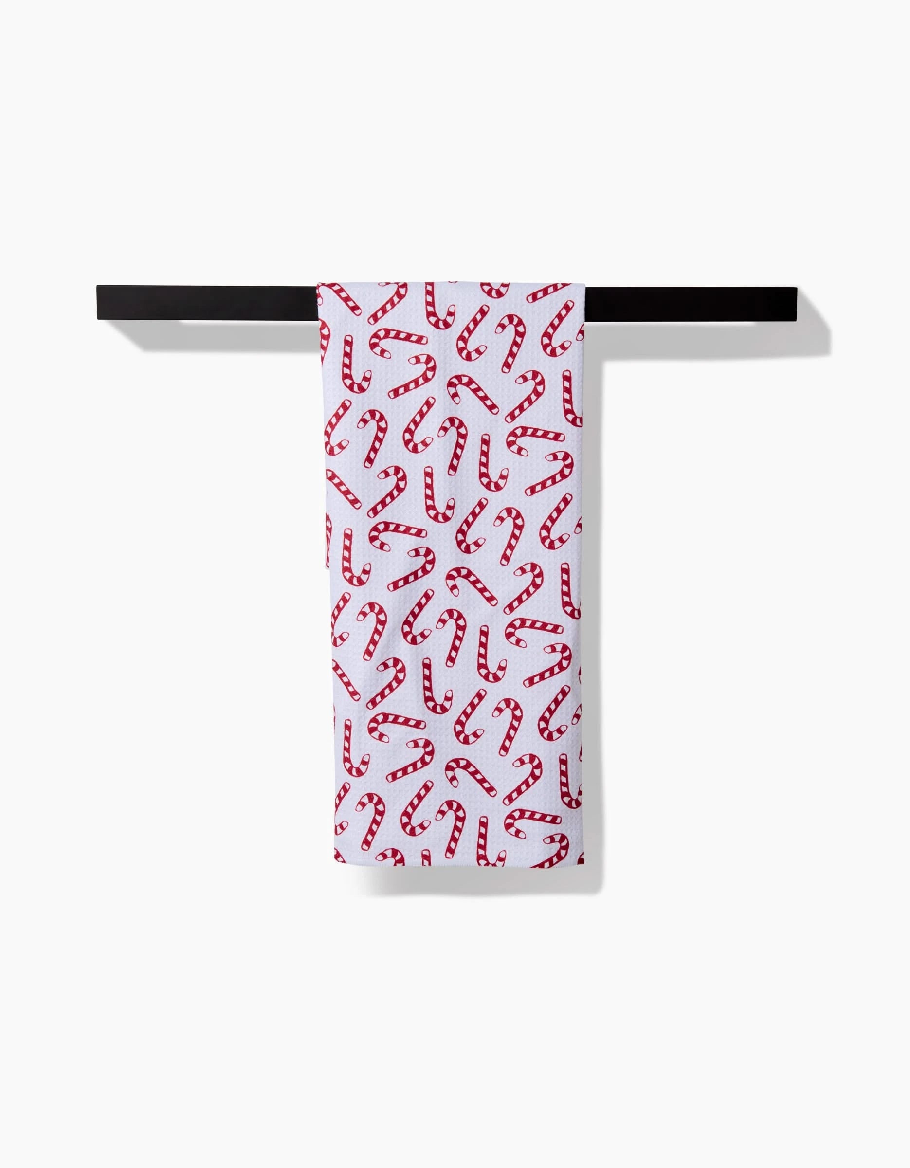 The Aubrey Fairchild Christmas Candy Canes tea towel, crafted from ultra-absorbent recycled materials, features a festive red and white candy cane pattern and hangs neatly on a black bar against a plain white background.