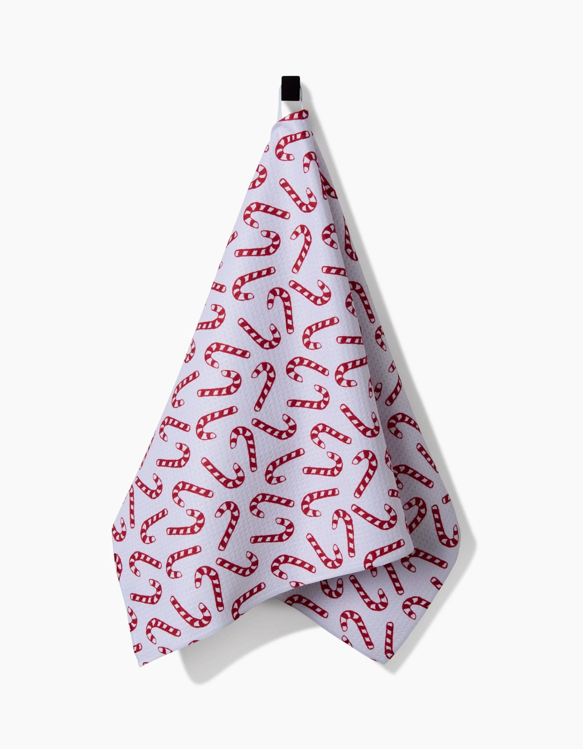 The Christmas Candy Canes tea towel by Aubrey Fairchild, made from ultra-absorbent recycled materials, features a festive red candy cane design and hangs from a black loop against a plain white background. Eco-friendly and stylish for the holidays.