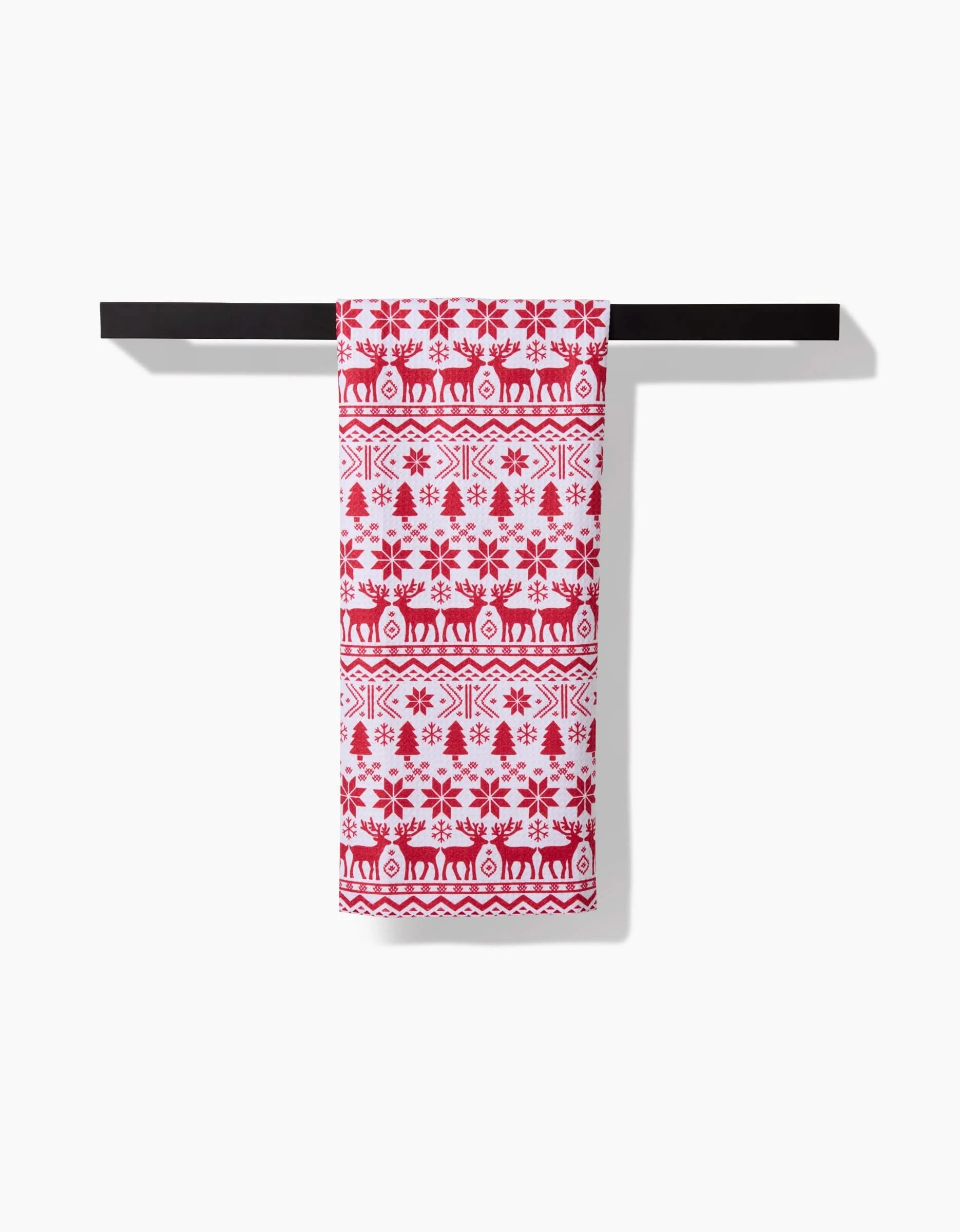 A Christmas Jumper by Hufton Studio, featuring red geometric and floral patterns on white fabric, is folded and displayed neatly on a black bar against a plain white background.