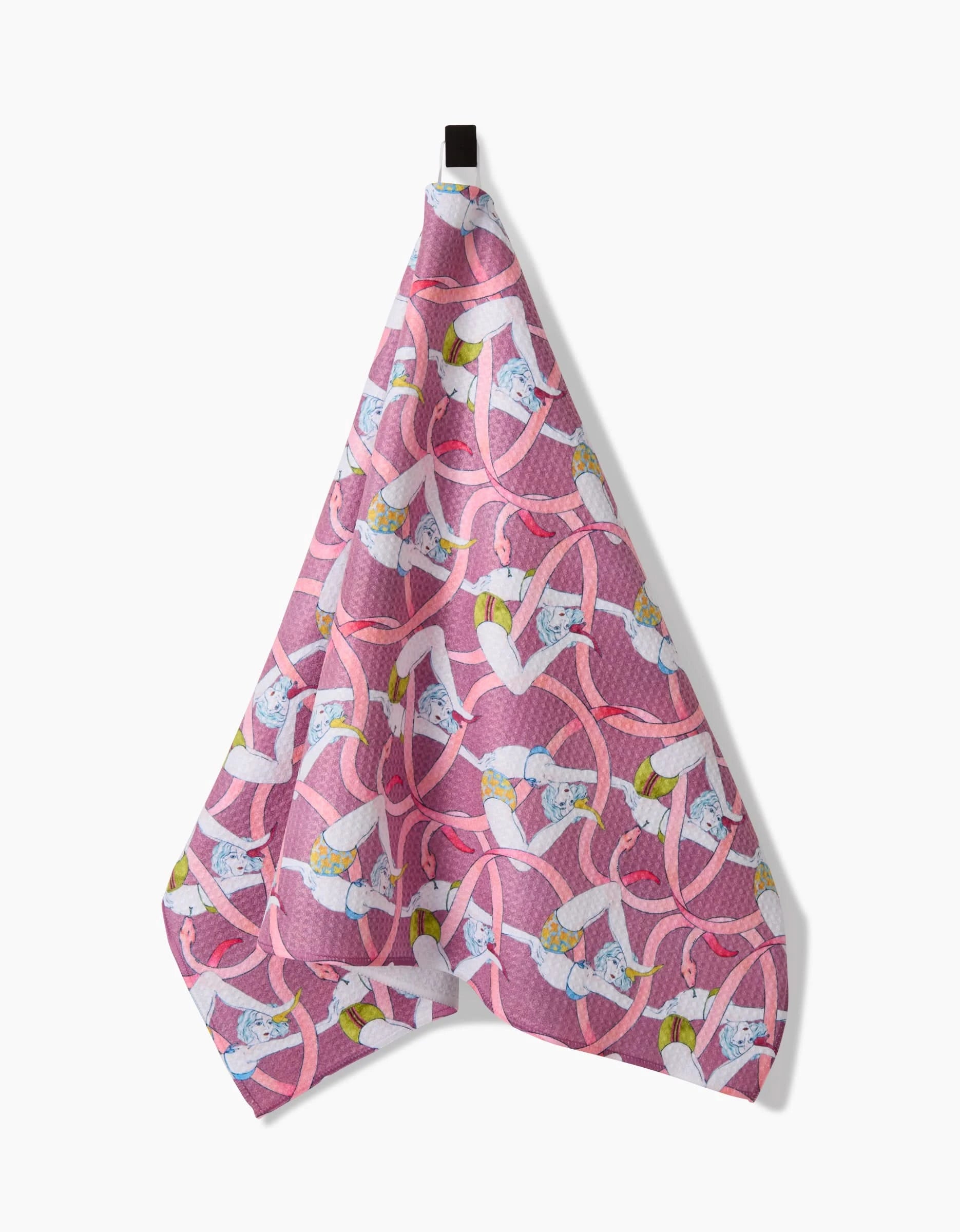 A Maayan Alper-Swan Circus Geoweave™ tea towel in pink, featuring white birds, yellow accents, and pink interlocking loops, hangs from a black hook against a white background.