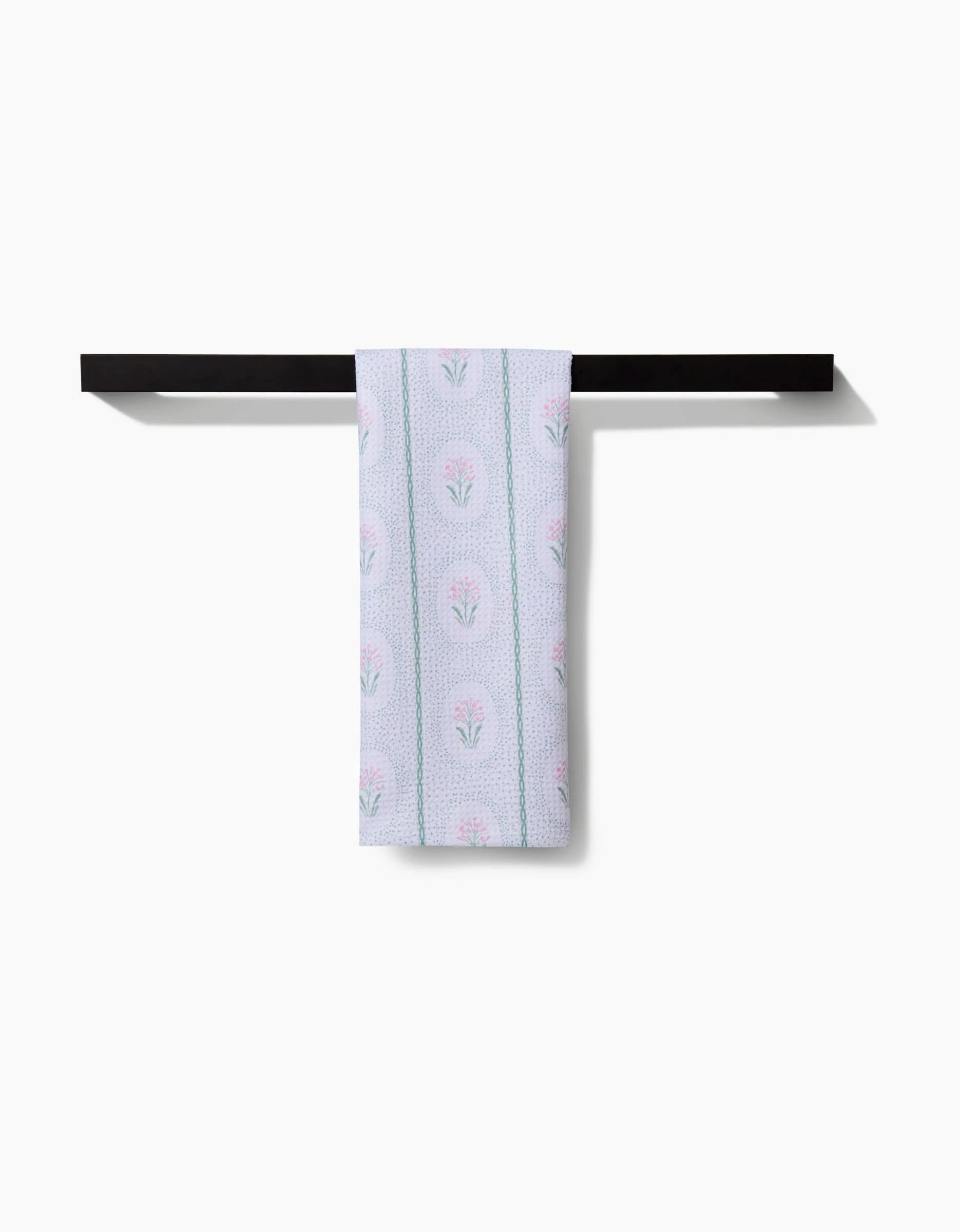 The Hufton Studio Cottage Dainty Spotted Tea Towel, featuring a soft pink and green floral pattern, is made from ultra-absorbent Geoweave fabric—ideal for everyday use and shown neatly folded on a black towel bar.