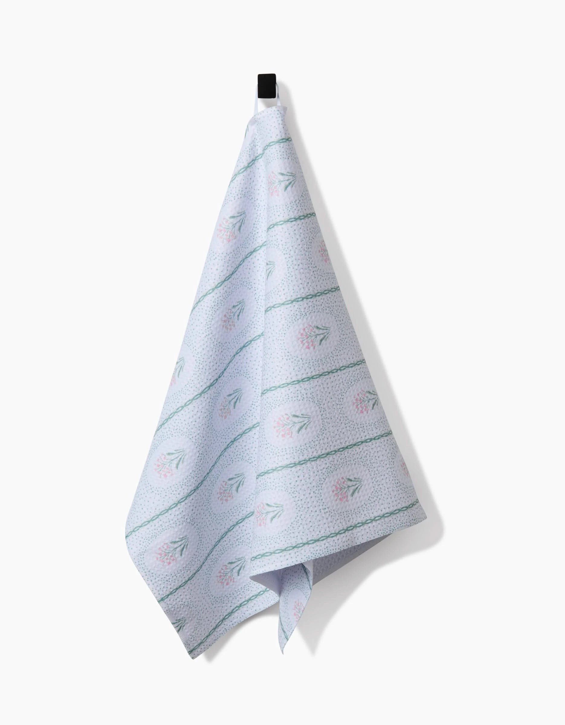 The Cottage Dainty Spotted Kitchen Tea Towel by Hufton Studio hangs from a black hook on a white background, featuring light blue tones and green stripes, crafted from ultra-absorbent Geoweave fabric for superior performance.