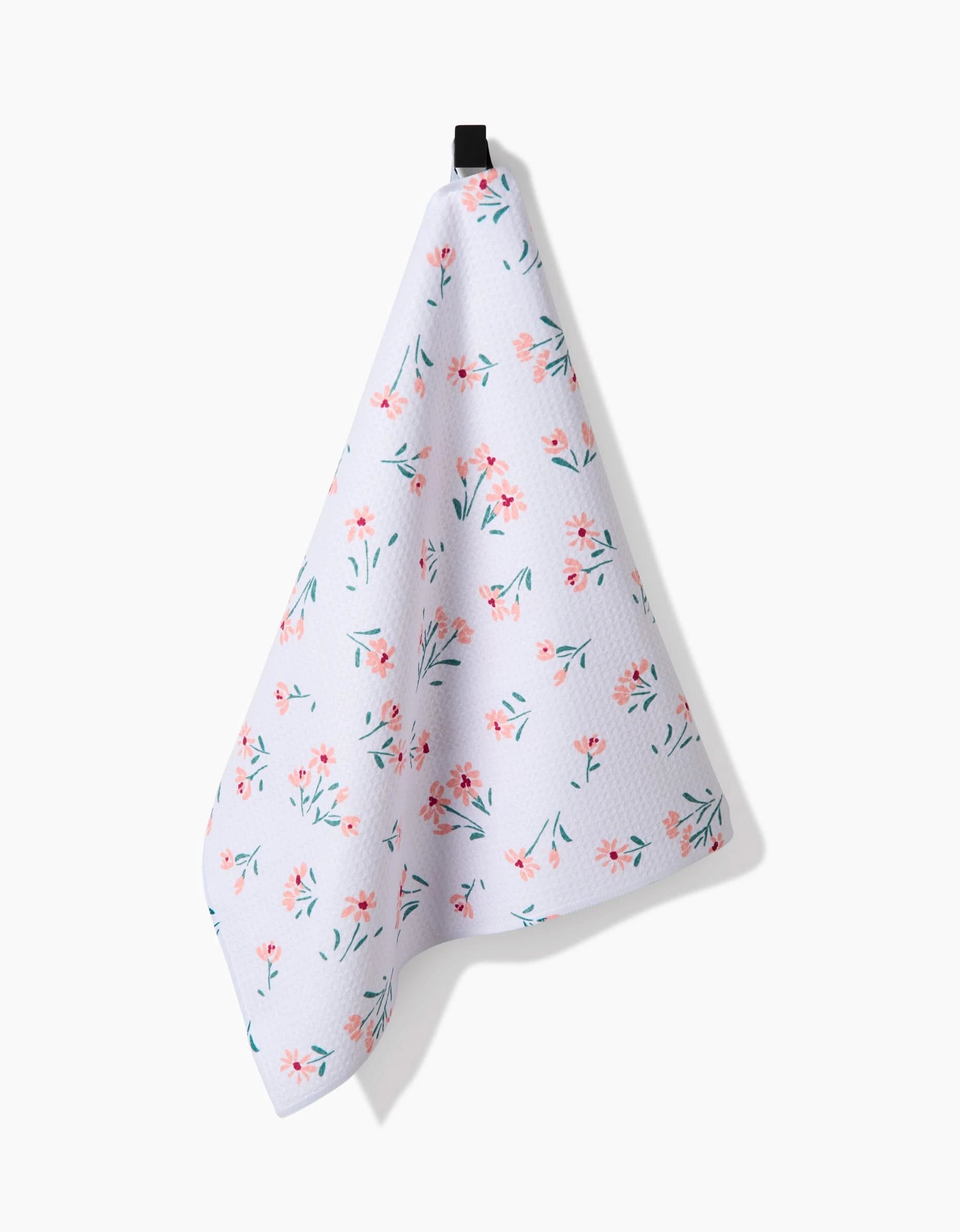 The Cottage Garden tea towel by Hufton Studio, made from recycled materials, showcases a pink and green floral pattern and hangs from a black loop against a plain white background.