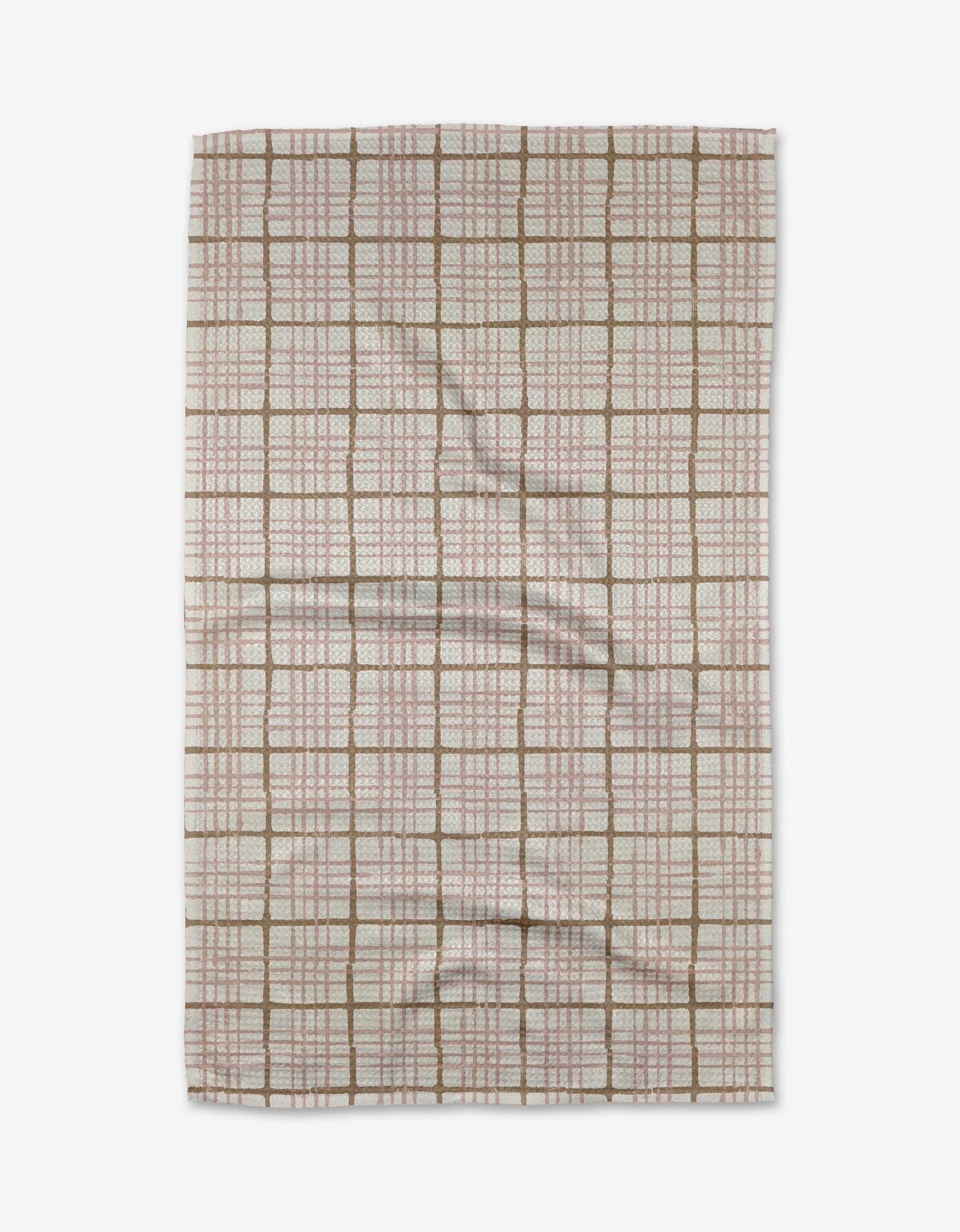 The Studio Jeannot Crossover tea towel features a rectangular Geoweave fabric with brown and red grid lines on a light background, displayed flat with slight wrinkles. This eco-friendly textile blends style with sustainability.