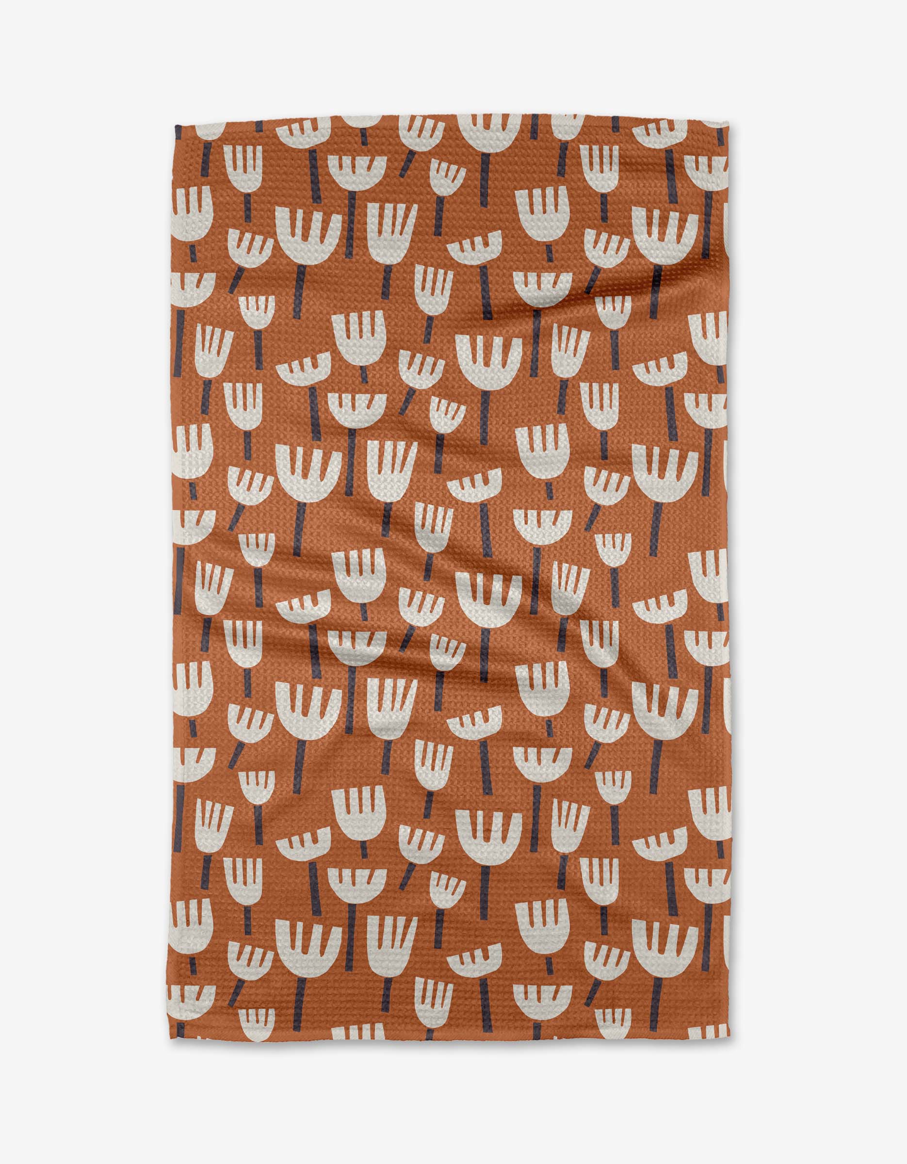 The Cutout Flowers tea towel by Claire Iglesias is a brown rectangular Geoweave™ towel with neat rows of stylized white flowers featuring dark stems.