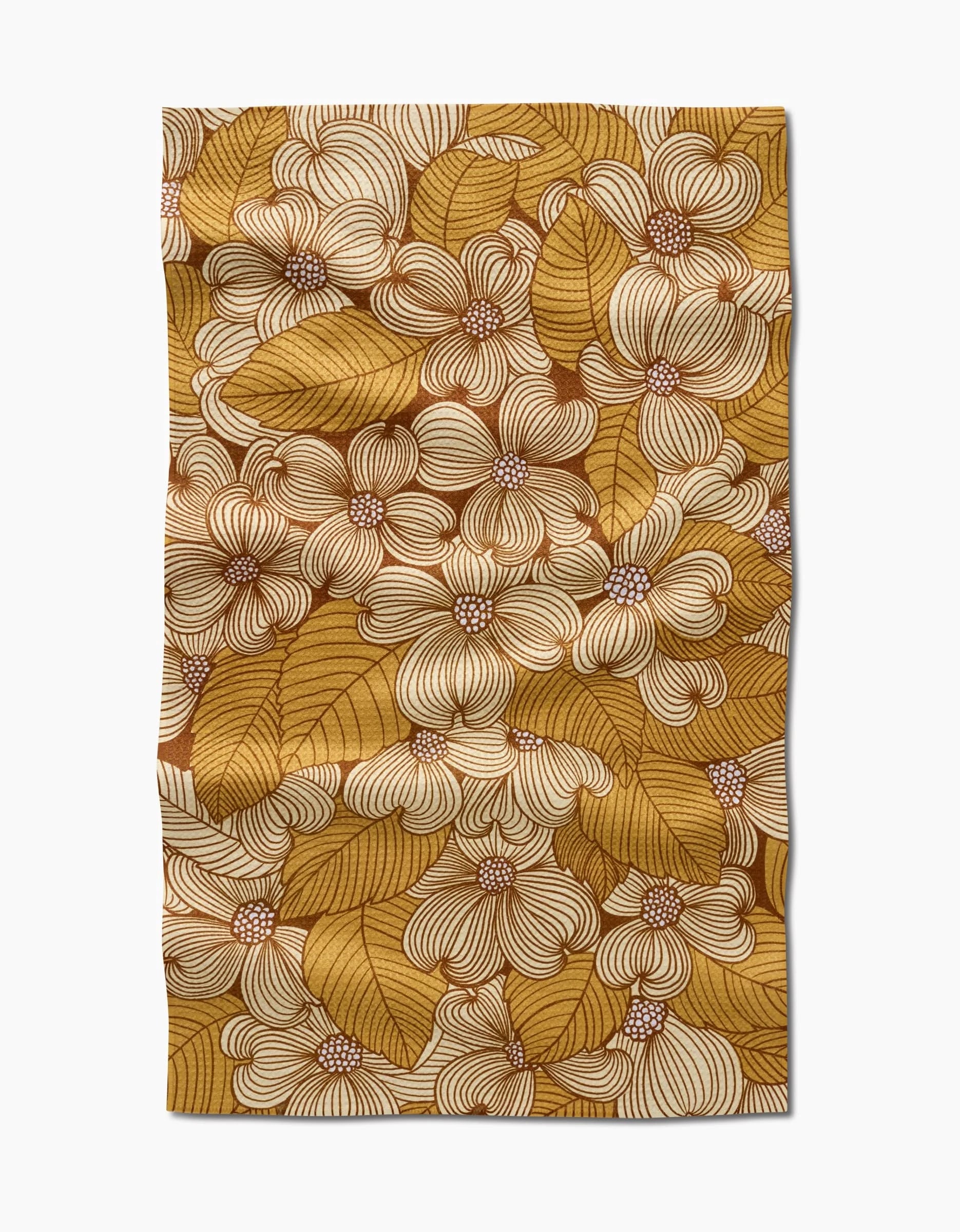 The Dogwood tea towel by Katie OShea is rectangular and made from recycled materials, featuring an intricate floral and leaf pattern in mustard yellow, brown, and cream for a dense, decorative look.