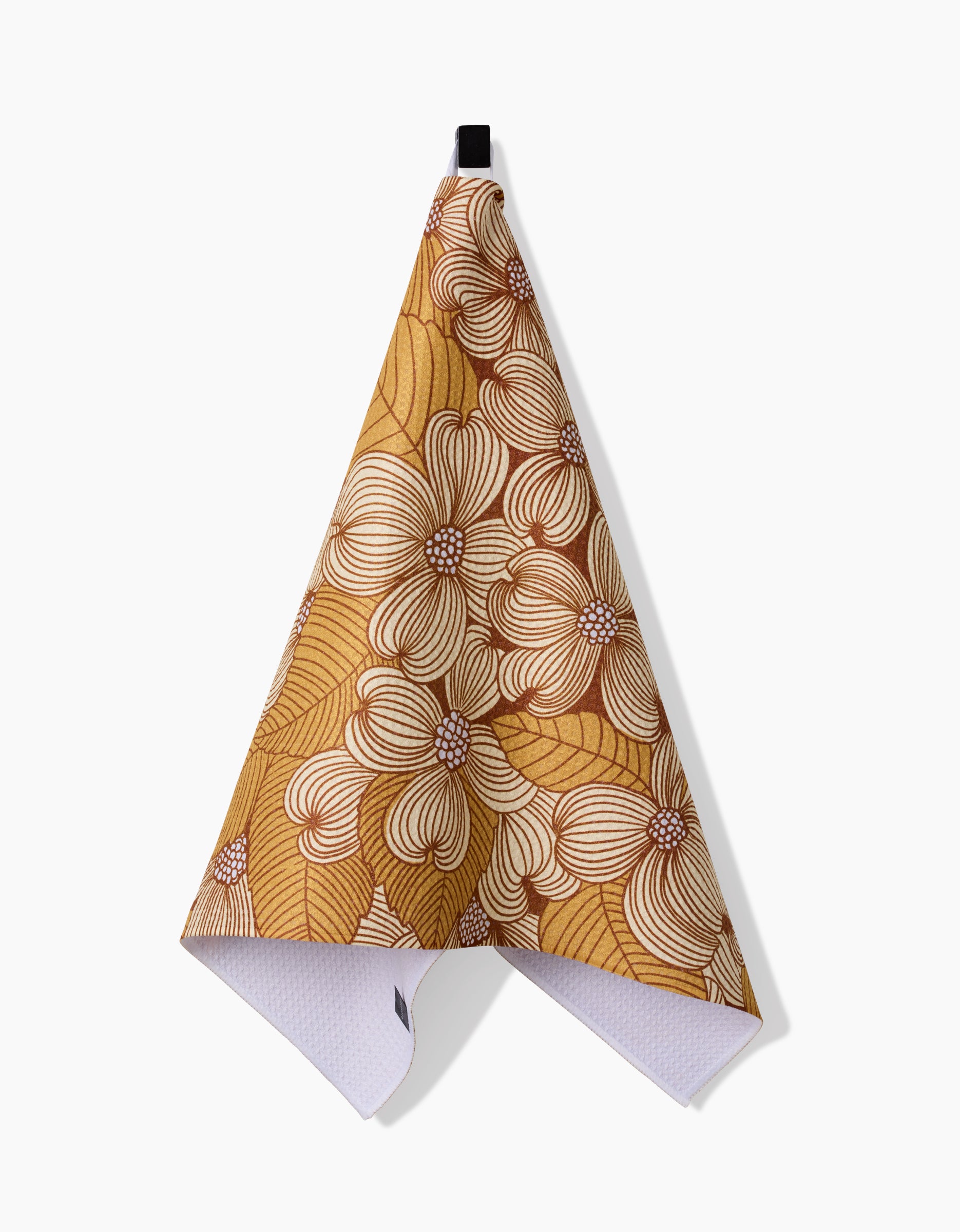 The Katie OShea Dogwood is a triangular hanging tea towel with a yellow, brown, and white floral pattern of large flowers and leaves. Made from recycled materials, it has a black loop at the top for easy hanging.