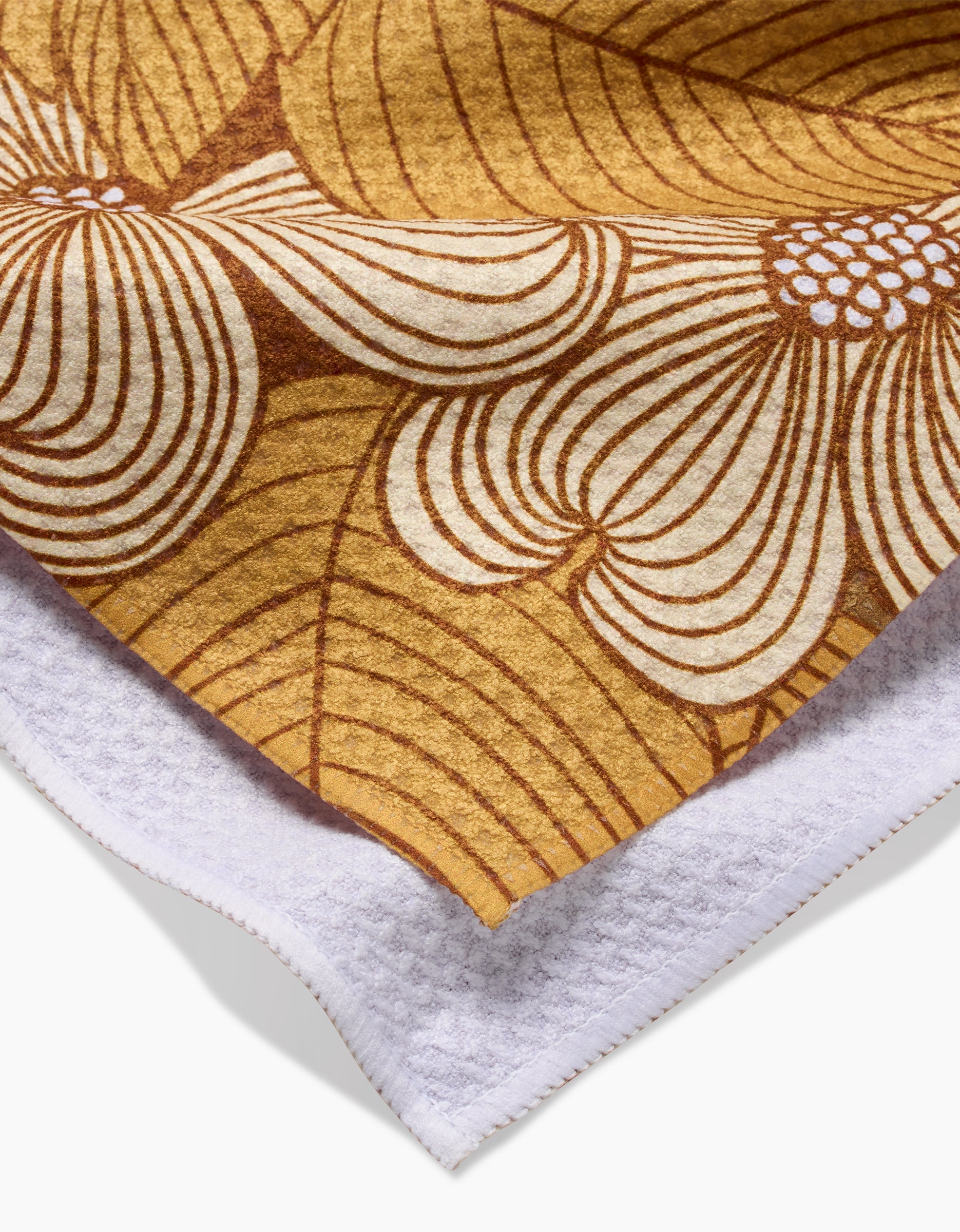 A close-up of the Dogwood tea towel by Katie OShea shows its brown and white floral design on one side and plain white textured Geoweave fabric on the other, highlighting its contrasting materials.