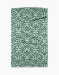The Ethereal Seaweeds tea towel by Jasmine Blooms Designs features a green leafy pattern on light gray recycled fabric with symmetrical stylized leaf motifs. The slightly wrinkled towel is displayed against a white background.