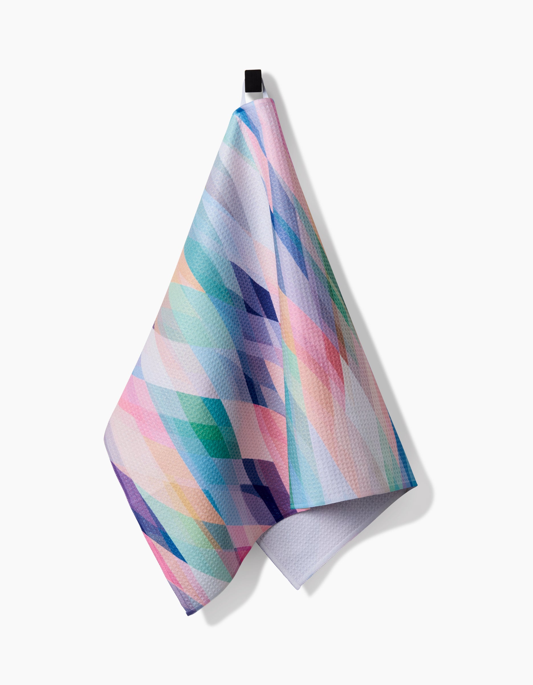 The Eventide tea towel by Rachel Parker, featuring a pastel geometric diamond pattern on soft Geoweave™ fabric, hangs by a small black loop against a plain white background.
