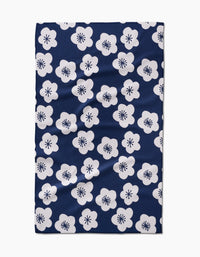 The GEOMETRY Every Sunday tea towel is dark blue, made from recycled materials, and features an even pattern of white five-petal flowers with black starburst centers.