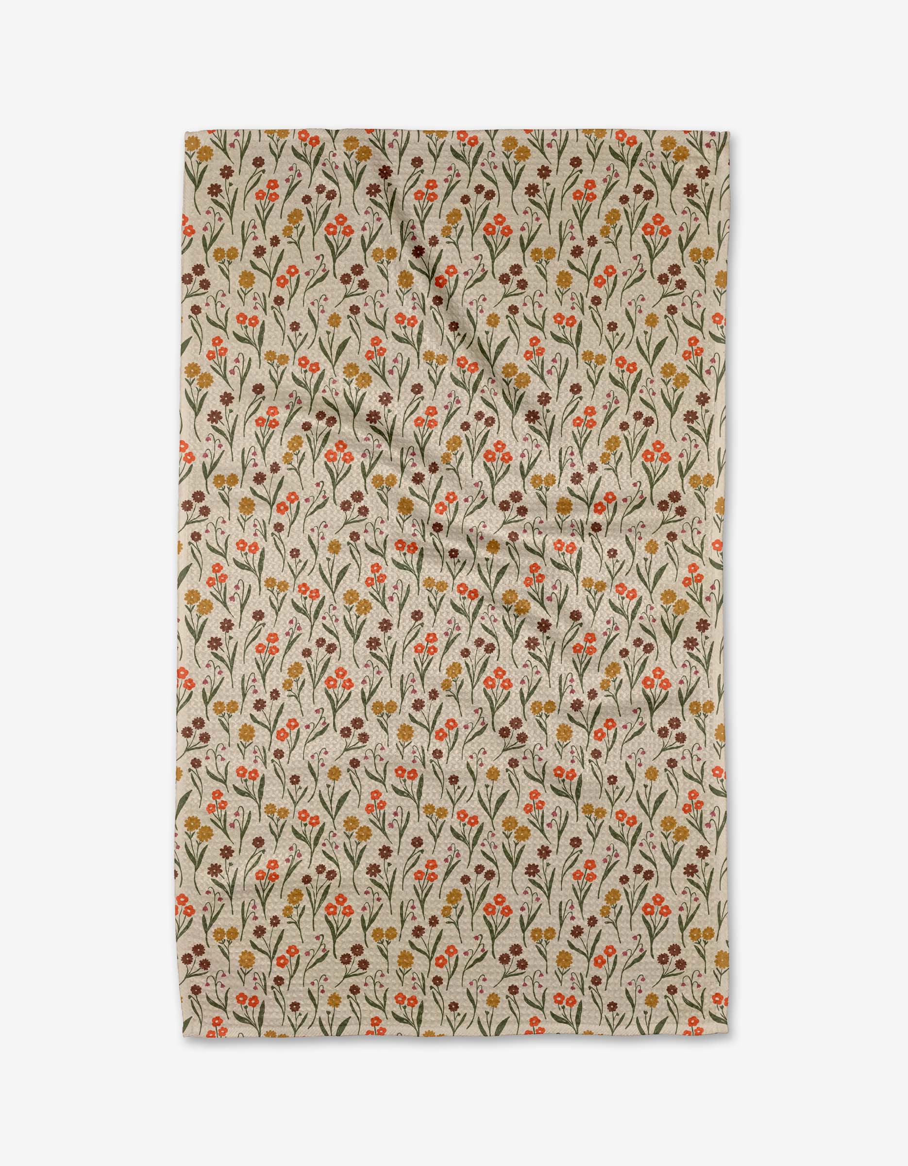 Kayla Ann’s Fall Blossom is a beige tea towel made from recycled materials, featuring small red and orange flowers, green leaves, and thin stems in a repeating pattern. The slightly wrinkled cloth is shown flat on a white background.