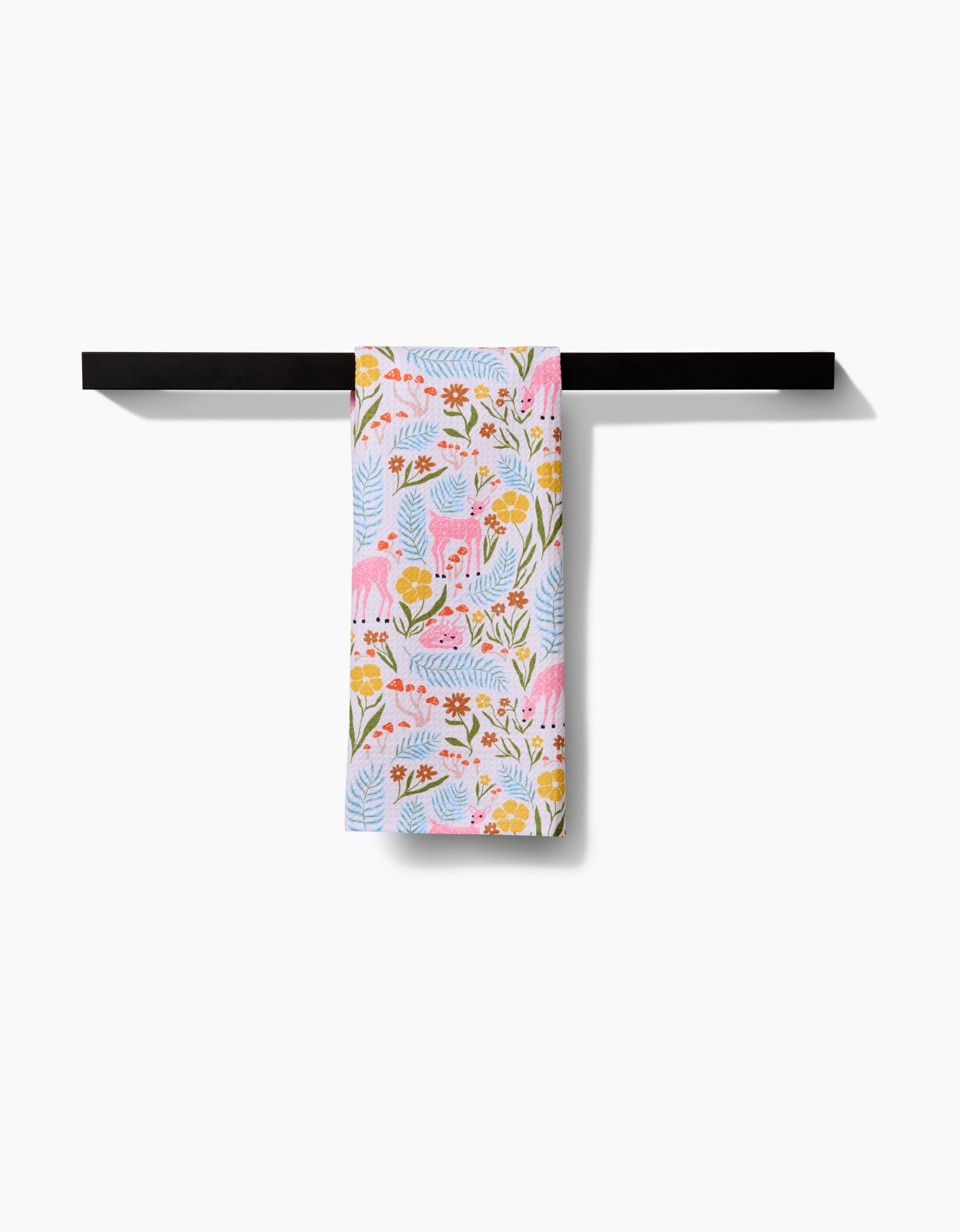 The Kayla Ann Fern and Fawn Tea Towel, featuring pink cats among yellow and red flowers with green leaves, hangs neatly over a black towel bar. Made of Geoweave fabric, it stands out against the white background.