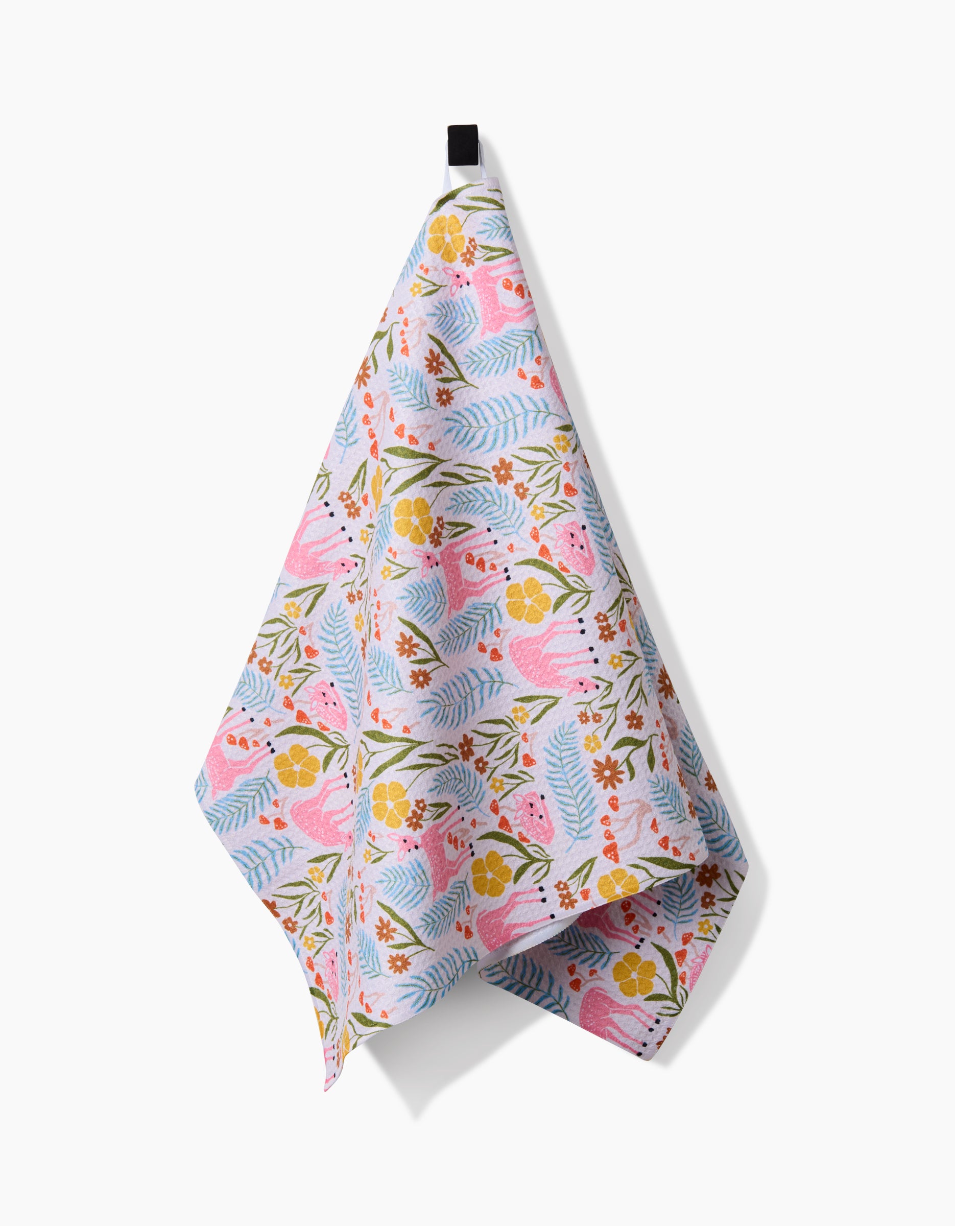 The Fern and Fawn Tea Towel by Kayla Ann, featuring a vibrant pink, yellow, blue, and orange floral pattern on durable Geoweave fabric, hangs on a black hook against a white background.