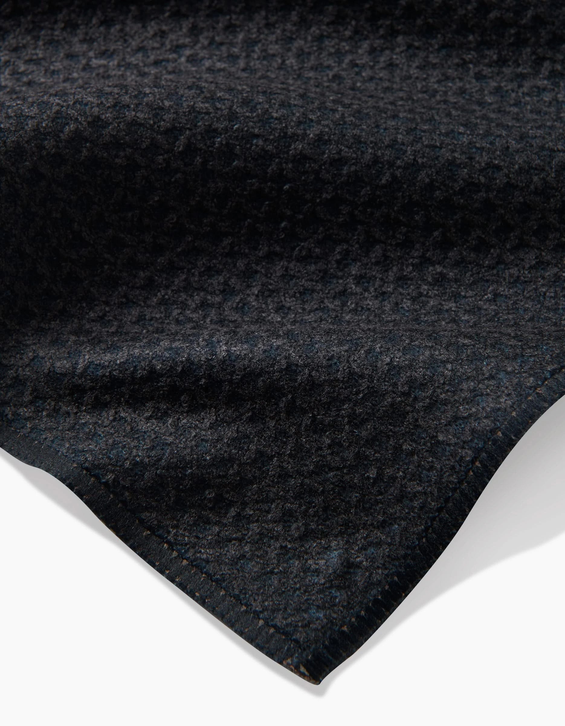 A close-up of the Fika tea towel by Anna Christian shows its dark, textured Geoweave™ fabric with a subtle geometric pattern and neat edge, set against a white background.