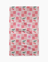 The Floral and Cherries tea towel by Letters By Shells features a pink and red checkered design with cherries and pink flowers, crafted from recycled materials for an eco-friendly touch.