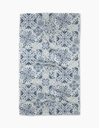 The Floral Medallions tea towel by Sarah Daugherty features a symmetrical blue and white floral and geometric tile-inspired pattern on a crisp white background.